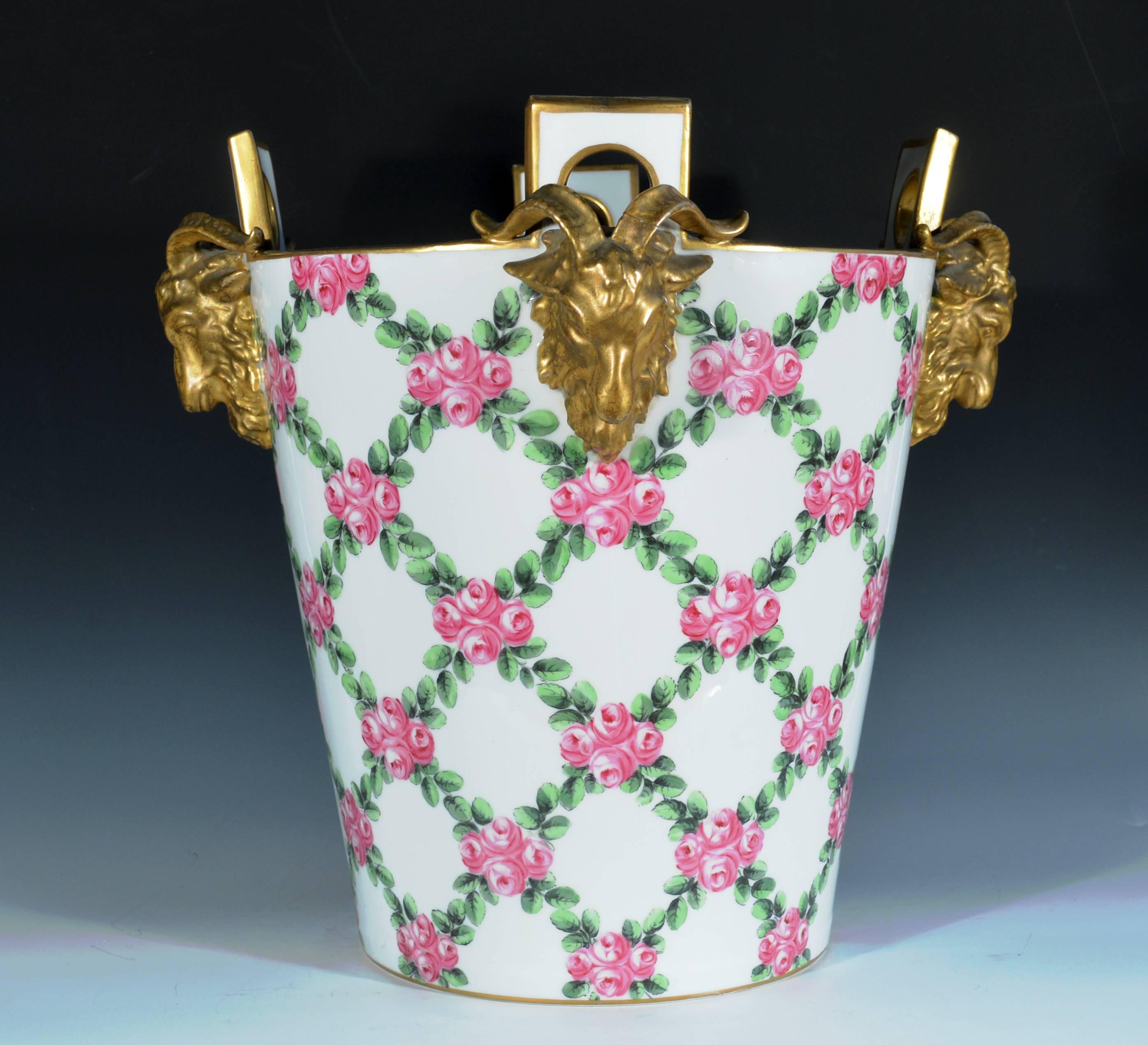 Paris Porcelain Sèvres-style Milk Pail,
late 19th century 

The cylindrical pail with four raised handles with ram head gilded terminals is painted with trellis-work roses with green leaves.

Mark: Pseudo- Sevres AA mark.

 