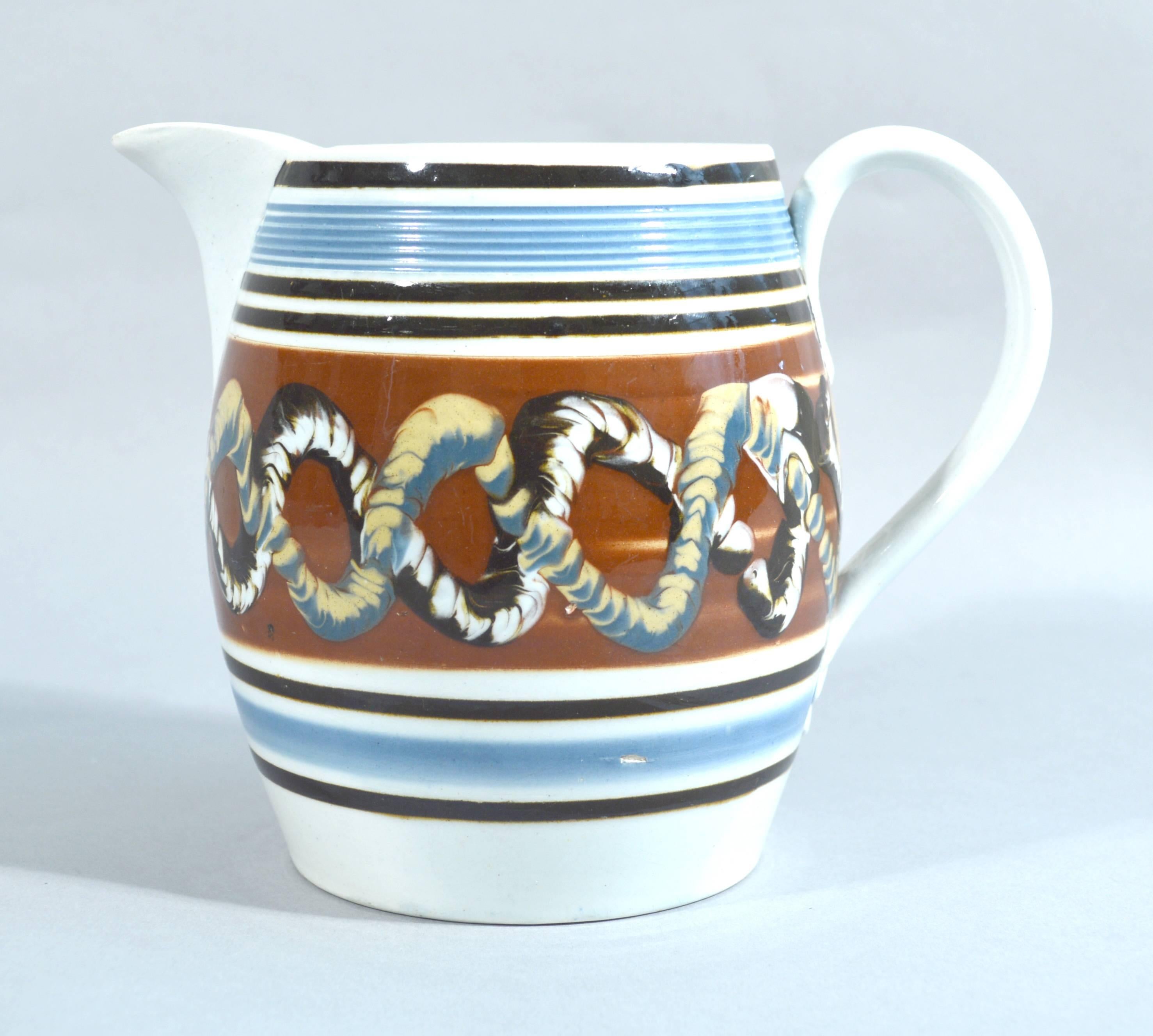 Mocha pearlware jug with double earthworm design,
circa 1800-1830.

The mocha pearlware jug or pitcher is decorated with a double-earthworm design on a central brown panel. To the top is a molded reeded band in a sky blue and below a narrower