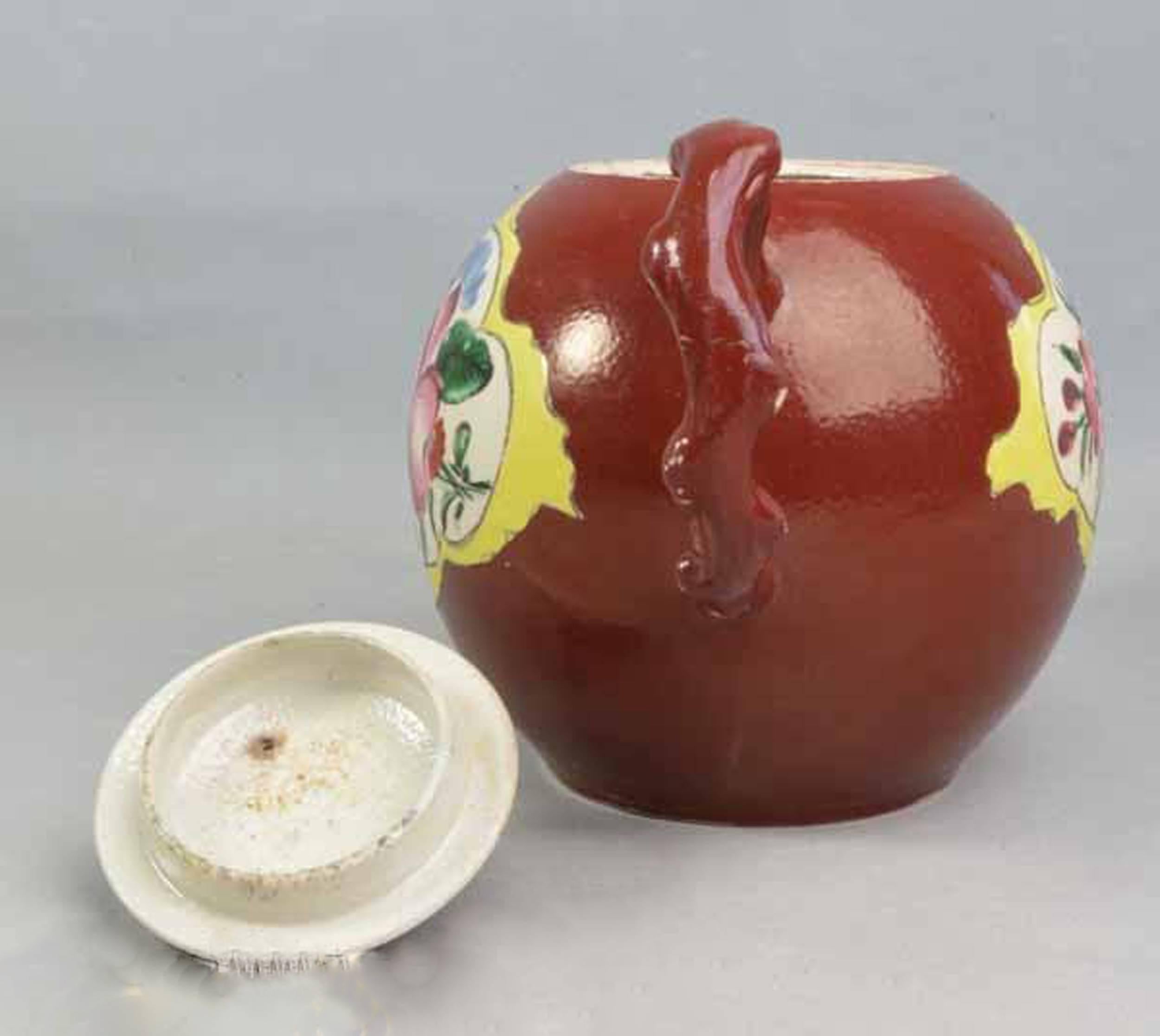Plum red-ground saltglaze stoneware teapot & cover, 
circa 1760.

The teapot with crabstock handle and spout has one of the rarest ground colors to be found in saltglaze stoneware. Each side is painted with naturalistic flowers within a yellow