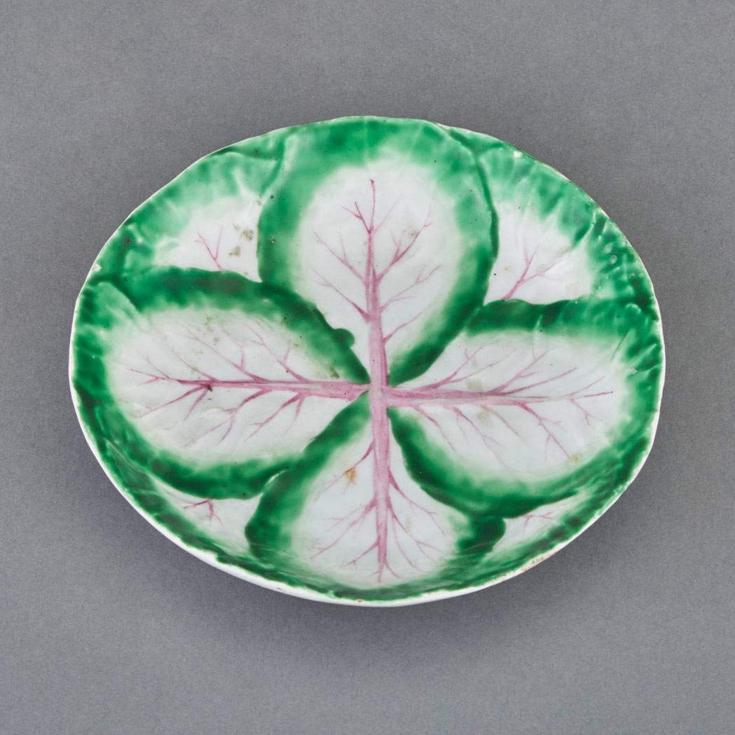 Longton hall porcelain four leaf molded saucer,
circa 1754-1757.

The Longton Hall saucer is moulded with three central large green leaves with puce veining atop four larger leaves.

Dimensions: 5 1/4 inches diameter x 1 inch high

Reference: