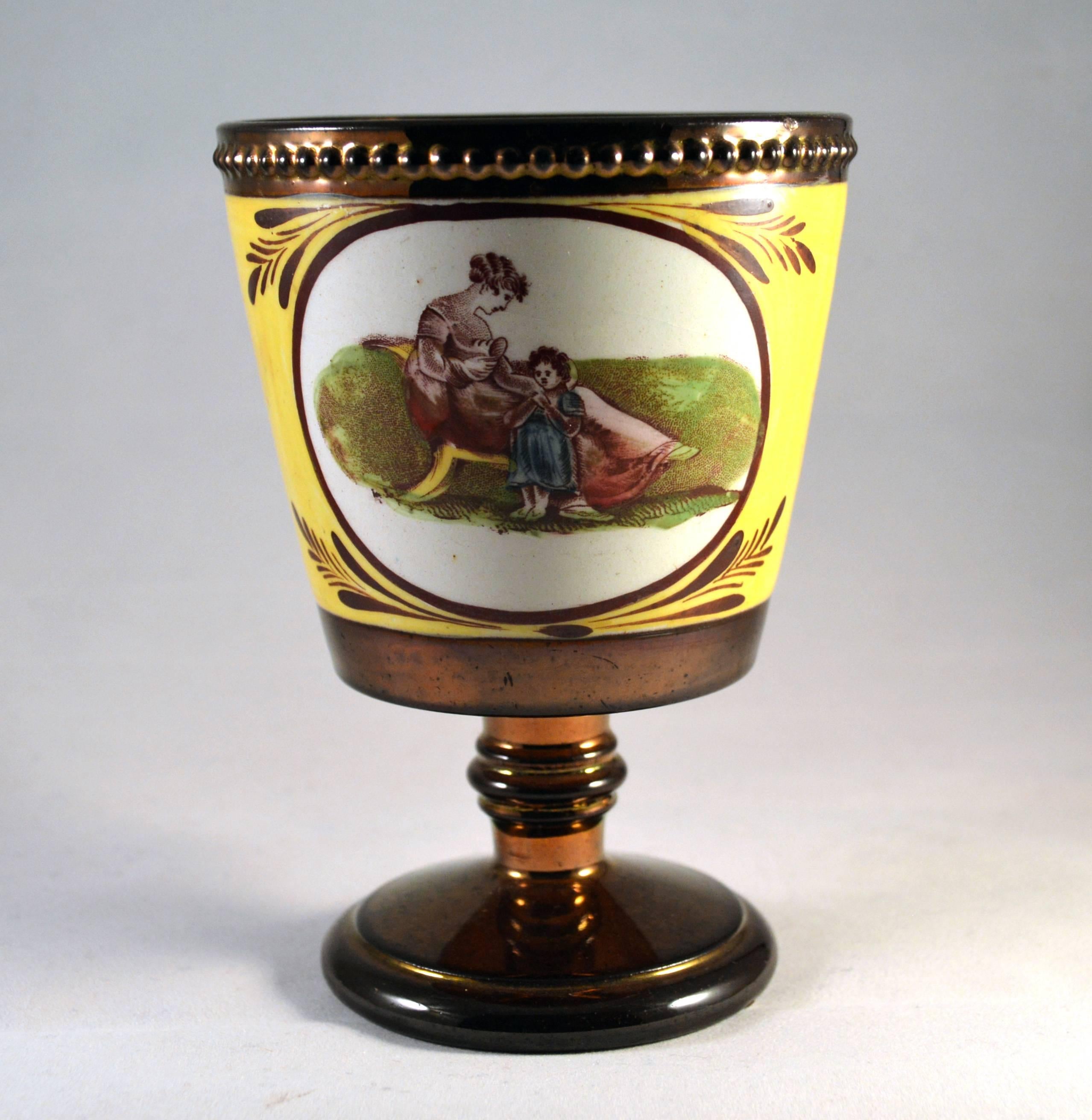English pottery copper lustre beaker with Adam Buck figures,
Possibly enoch wood, 
circa 1810-1830.

The copper lustre (luster) beaker with a yellow ground and circular panels to front and back containing Adam Buck style prints of mothers
