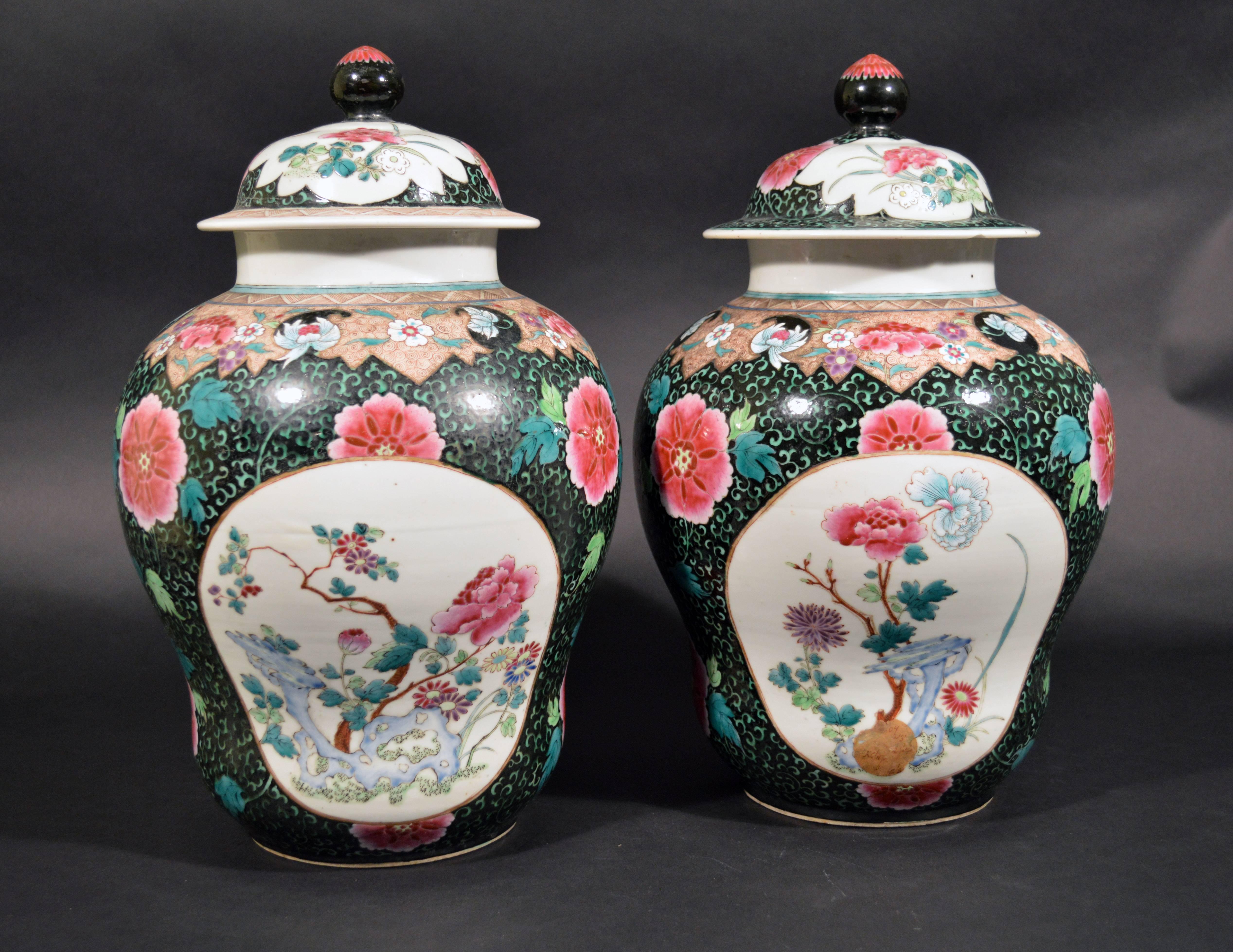 Chinese export porcelain famille rose black-ground large lidded vases each designed with two oval panels decorated with peonies and other flowers on stylized rockwork in blue.

The bodies of the gourd-shaped vases with a noir-ground randomly