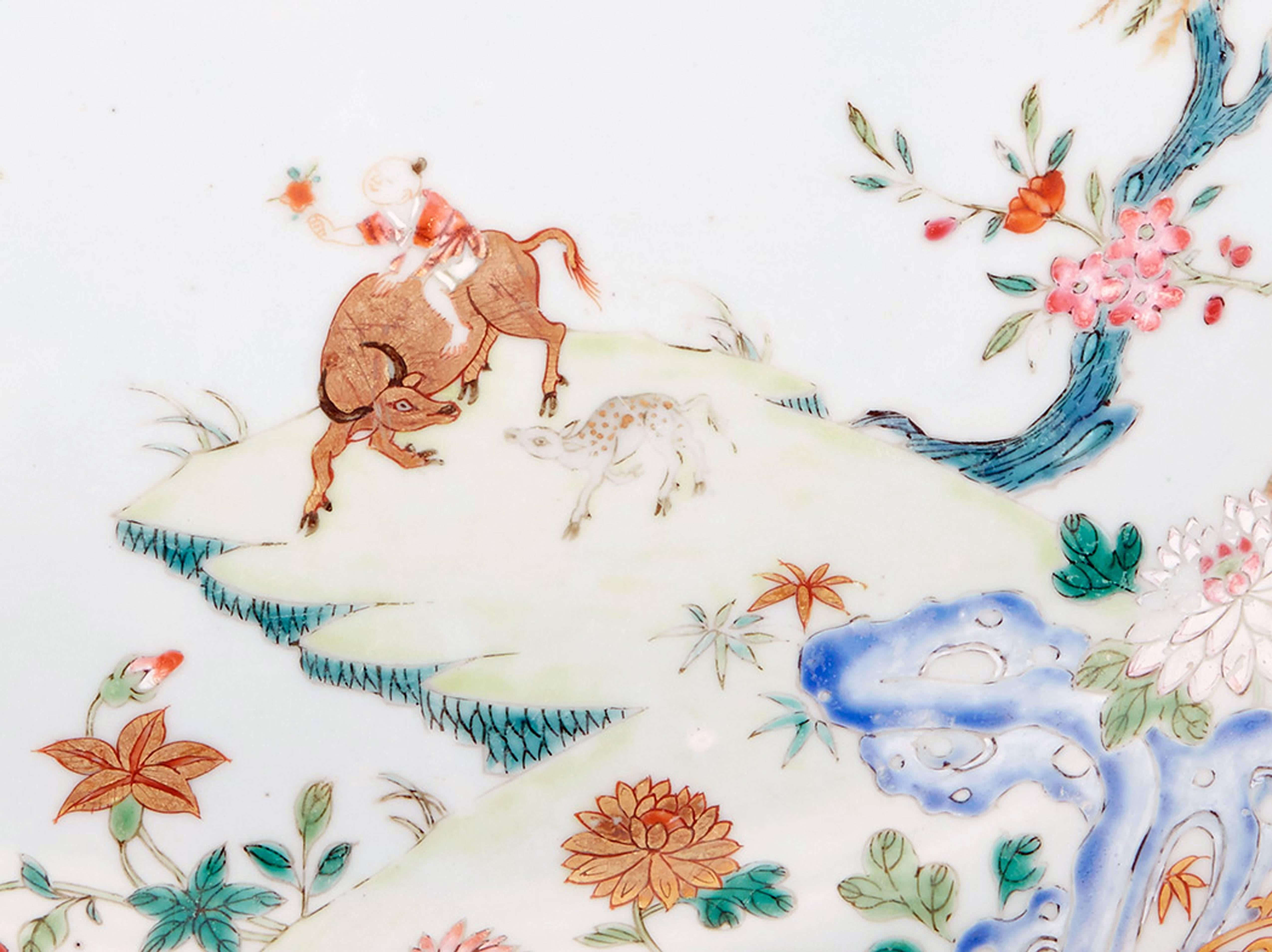 Chinese Export Porcelain Famille Rose dish with a boy on an ox,
circa 1750-1765.

Fine large shaped Famille Rose dish depicting a boy on an ox within a Chinese landscape with geese and butterflies to one side. A twisting leaf and vine band at the