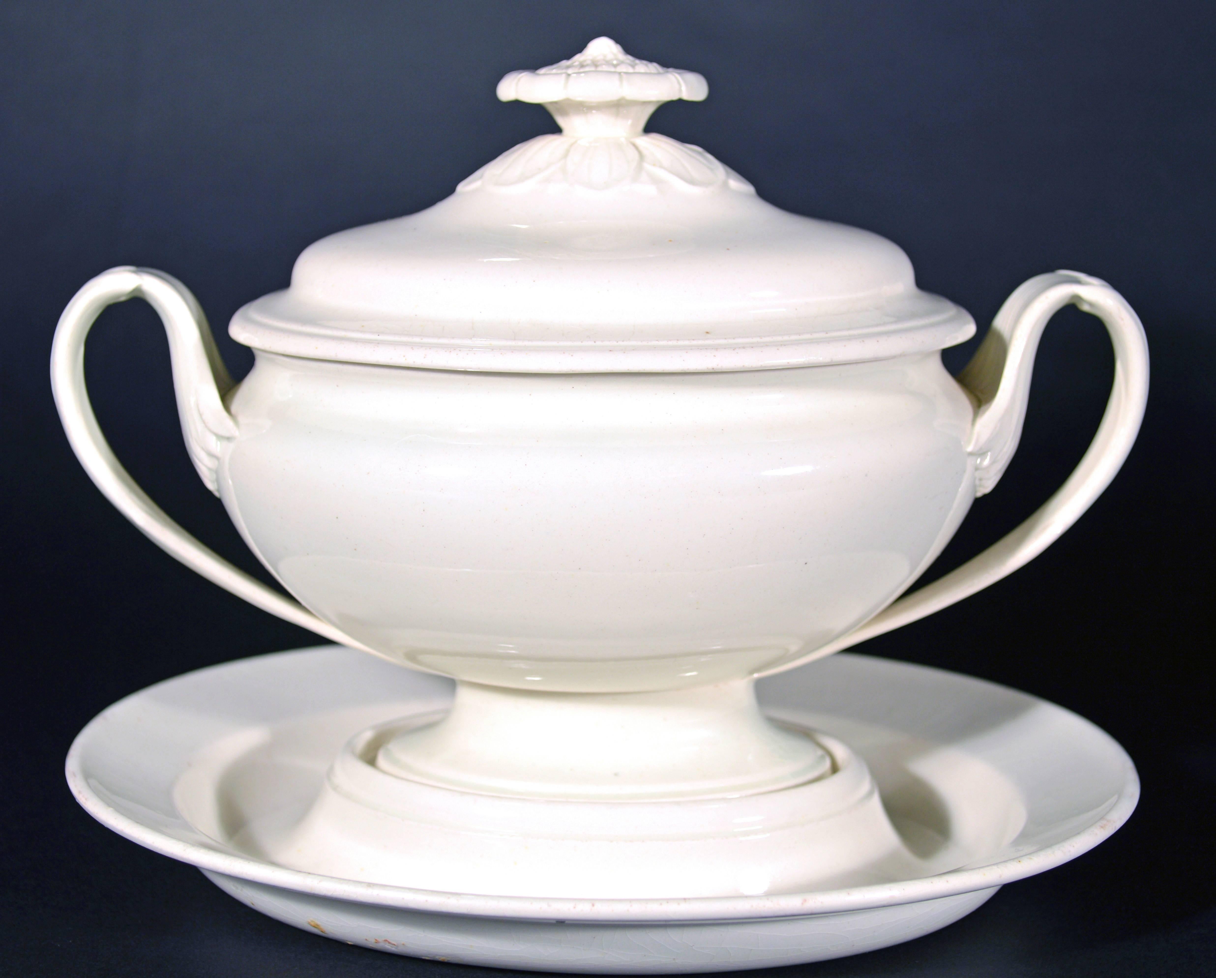 The Wedgwood creamware sauce tureen is an elegant and neoclassical footed oval tureen with slotted stand and cover. The finial is in the shape of a flower and the elongated looped handles feature a subtle botanical design.

Dimensions: 
Stand: 1