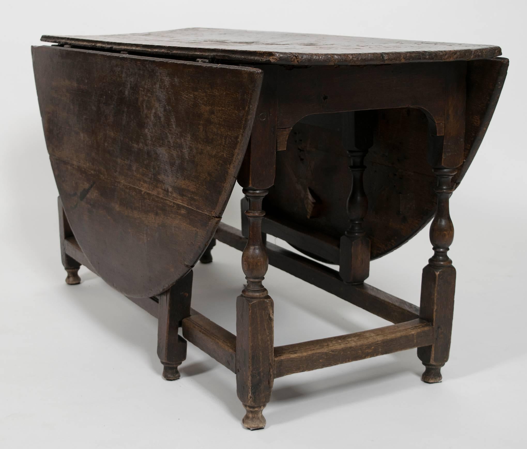 Early Georgian drop-leaf oak table with turned legs, circa 1750. Dimensions listed are for the table fully open. With leaves dropped, the table measures 19 1/2" wide.