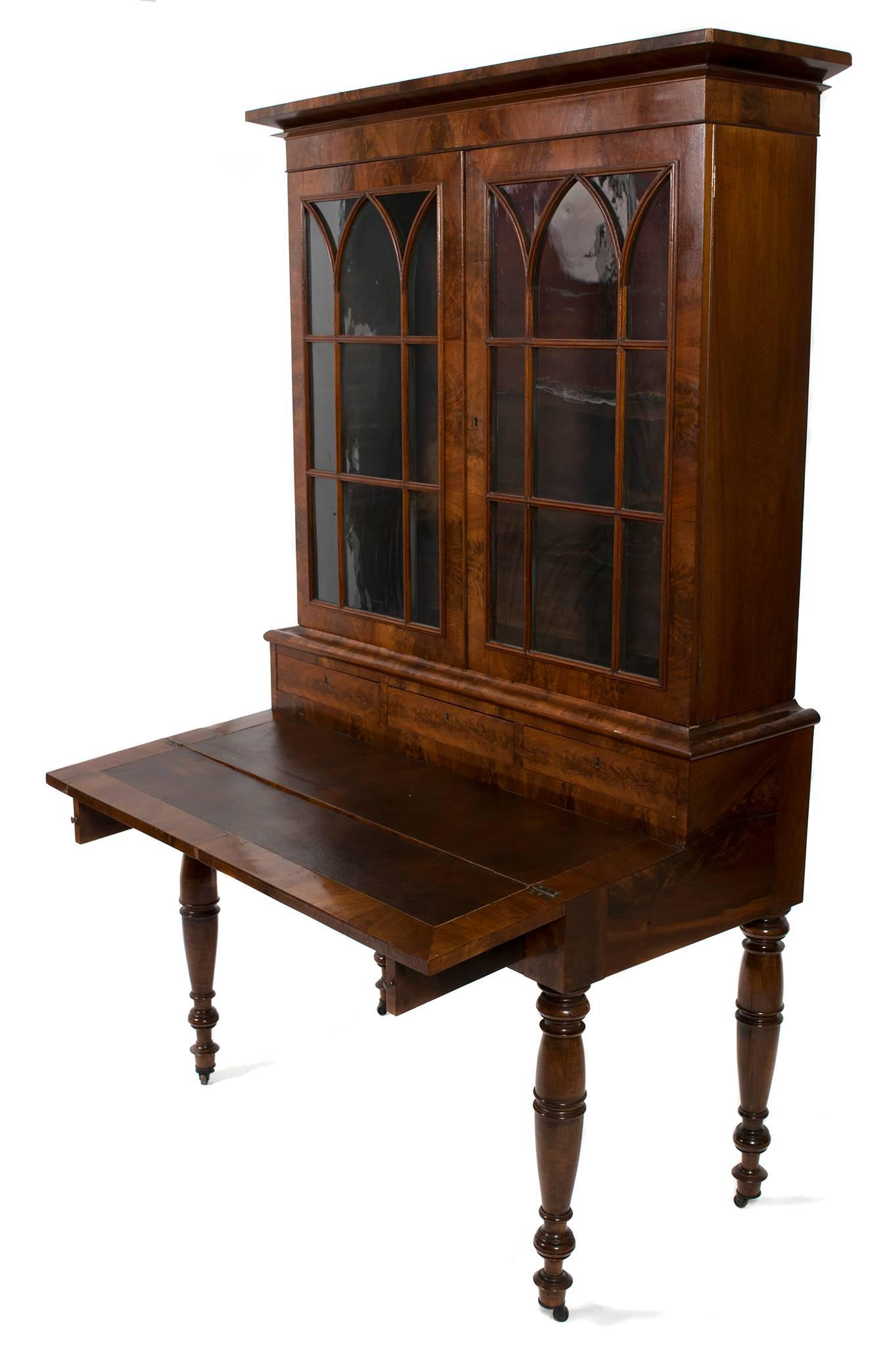 American mid-19th century mahogany secretary with bookcase, circa 1850-1860. Glass doors open to two shelves. Three small drawers at base of bookcase. One large drawer beneath hinged, leather top writing surface. Measures: Depth with drawer extended