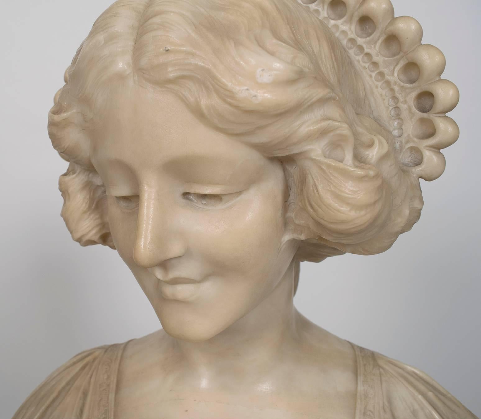 A lovely Italian marble female bust with original marble pedestal, early 20th century. Dimensions below are for pedestal with bust. Pedestal alone measures 39.5" H x 16.75" W x 12" D. Bust alone measures 17" H x 15.5" W x