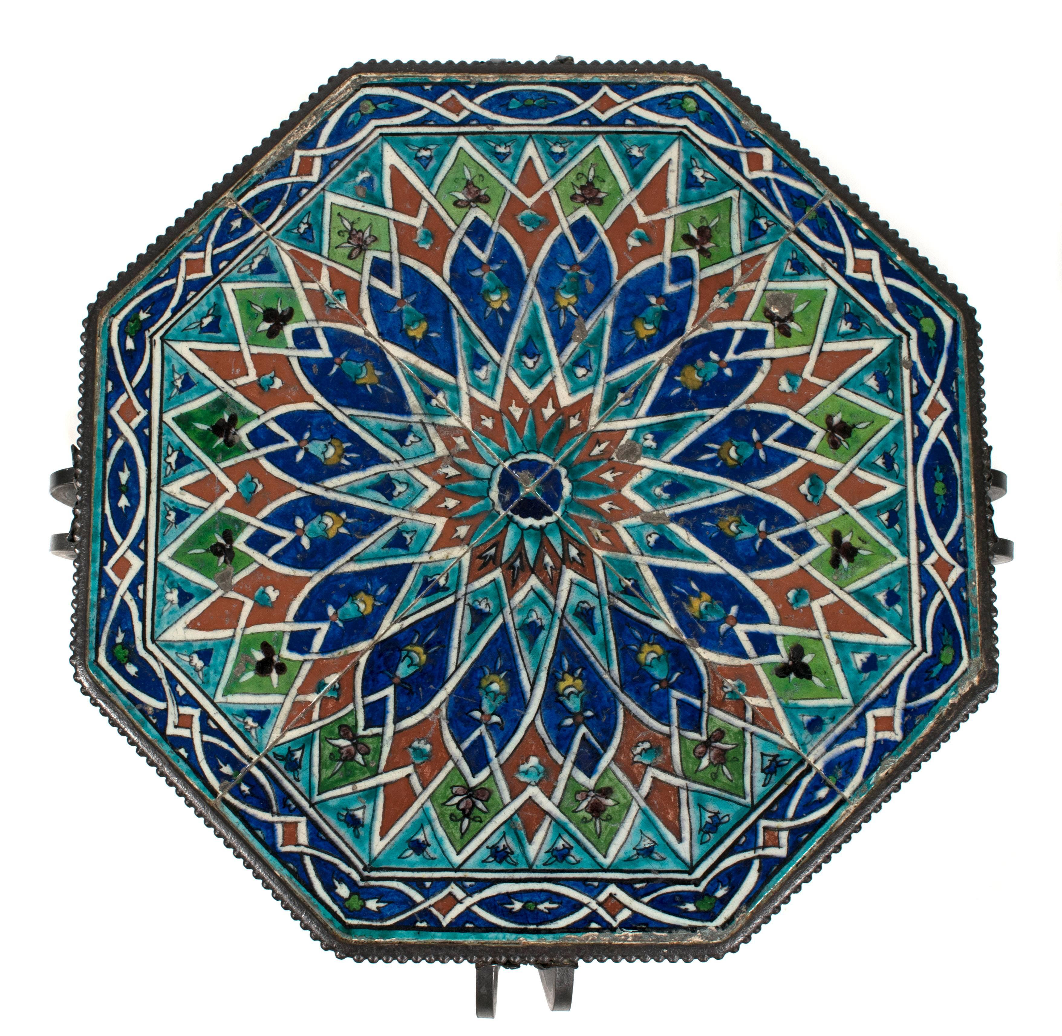 A French hand-wrought iron occasional table, circa 1930s. Four colorful terracotta tiles are inset into wrought iron surround with bead and floral decoration.