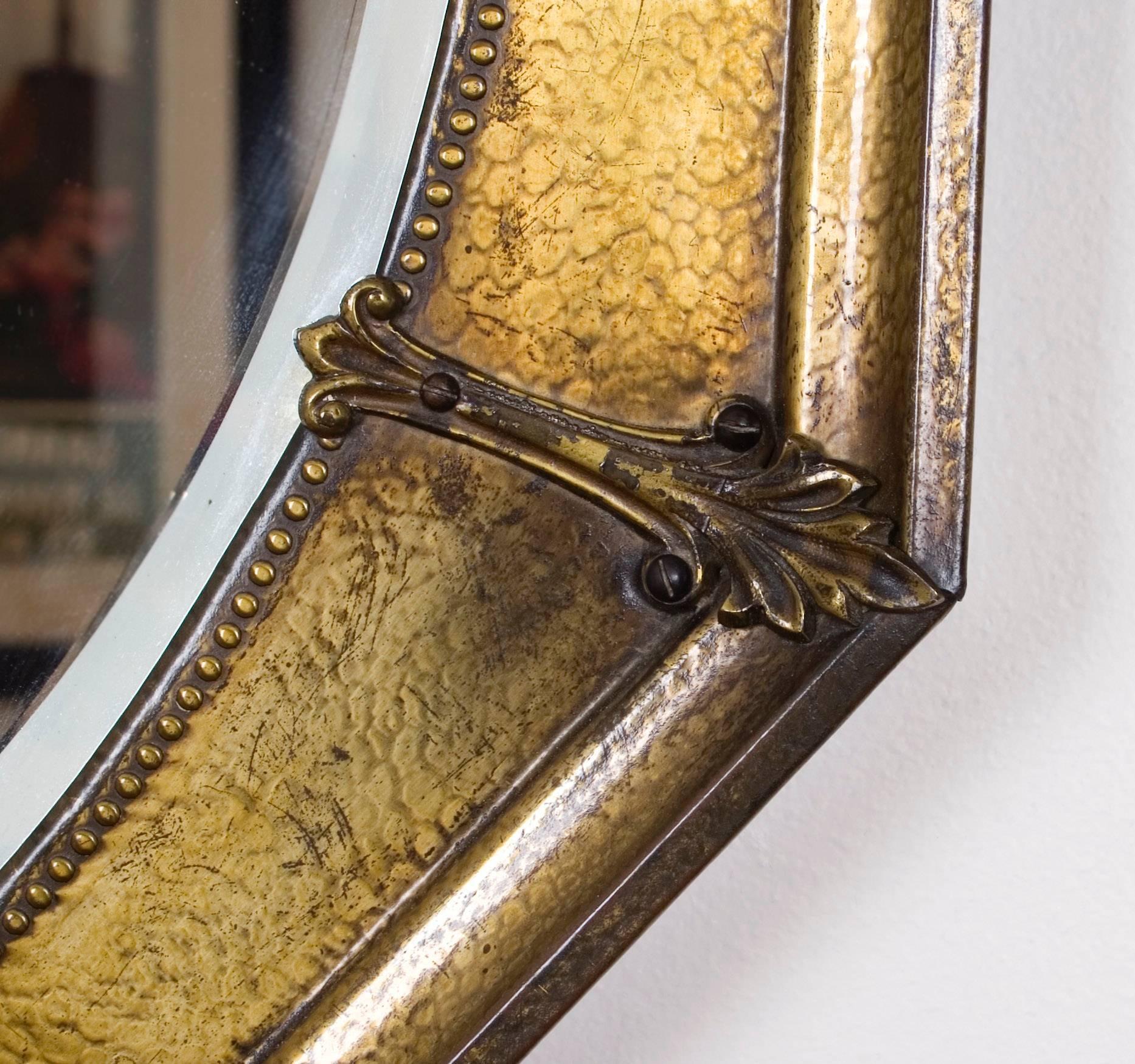 An Italian octagonal hammered brass wall mirror with bead and floral detail, early 20th century.