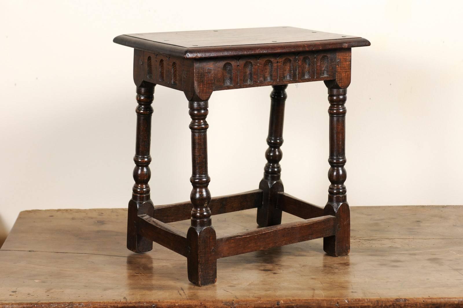 Not only are the turned legs and pegged construction lovely, but the carved Cathedral arches incised on the apron are unusual and decorative. This joint stool has many uses such as a pull up cocktail table or a stool by the fire place.
