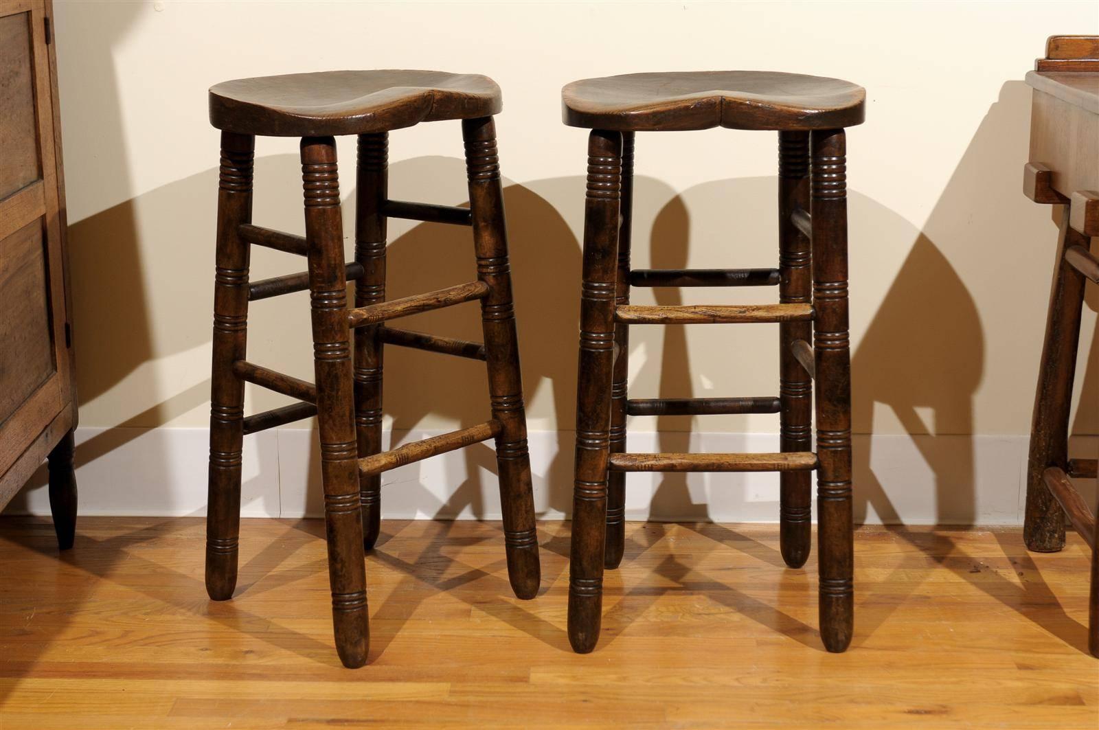 This is a pair of comfortable and charming stools that would add Ambience to your bar area. These stools sit beautifully and the legs and foot rests are hand-turned with ribbing to add character and detail. They were made in England out of oakwood.