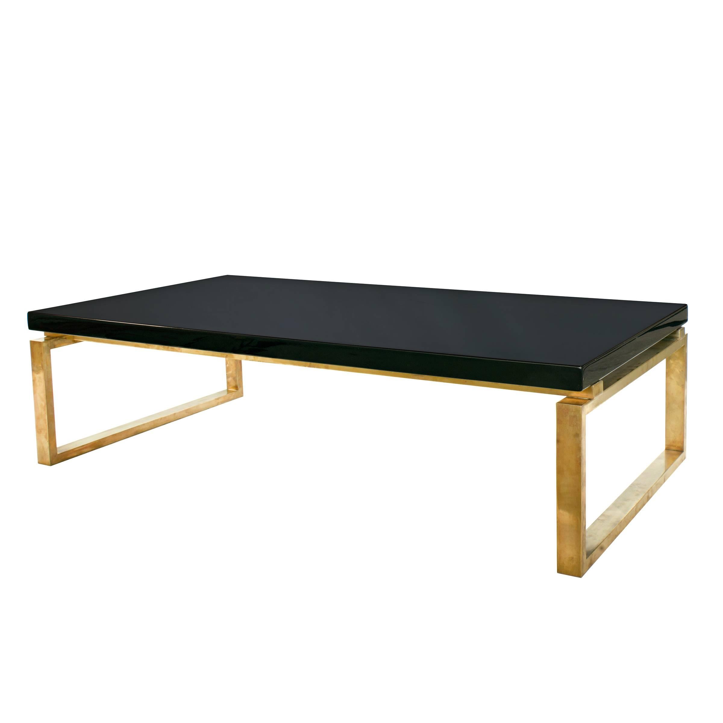 A very unusual low black lacquered coffee table with a square brass base. by Guy Lefevre