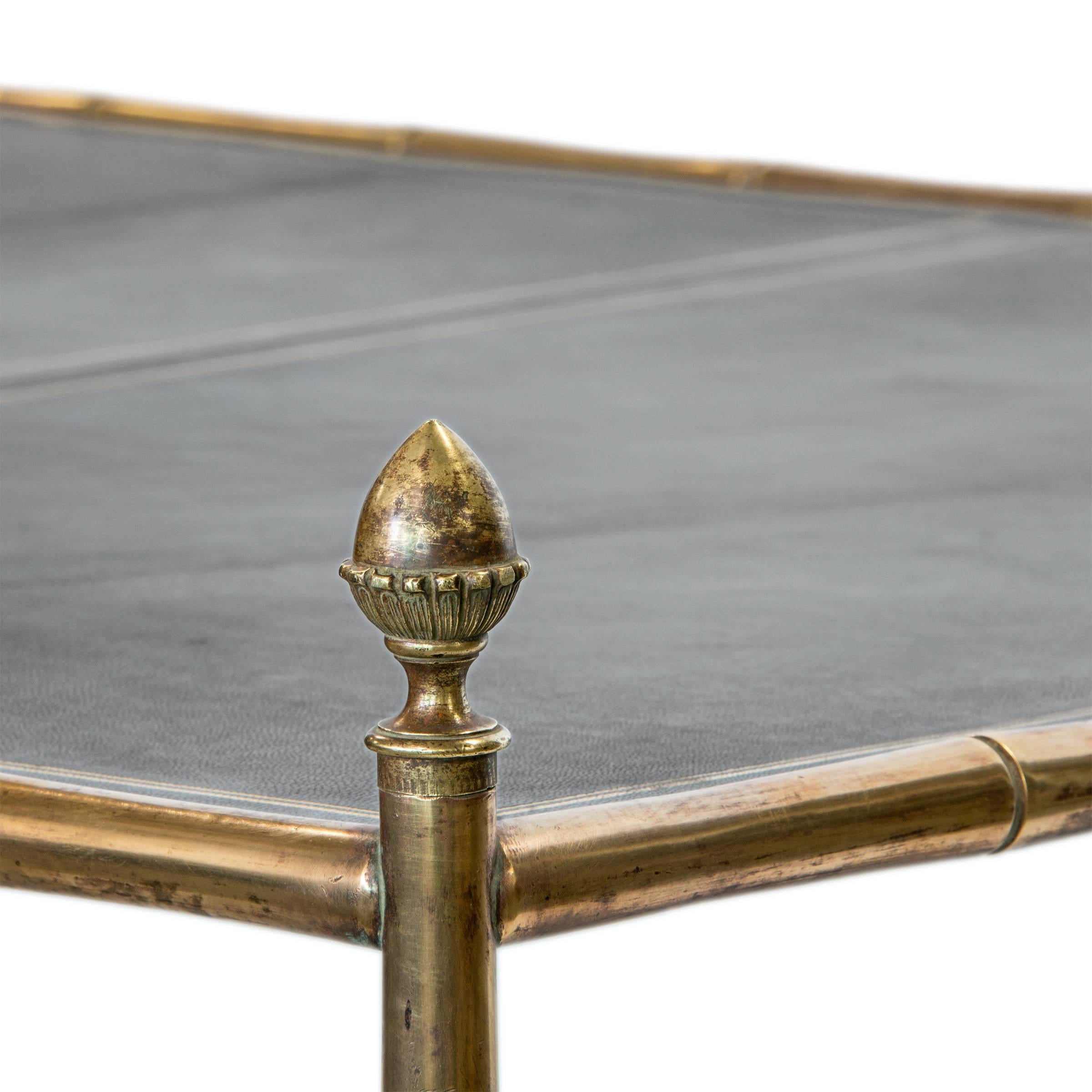 A very unique large brass bamboo coffee table with a three section gold tooled leather top on castors.