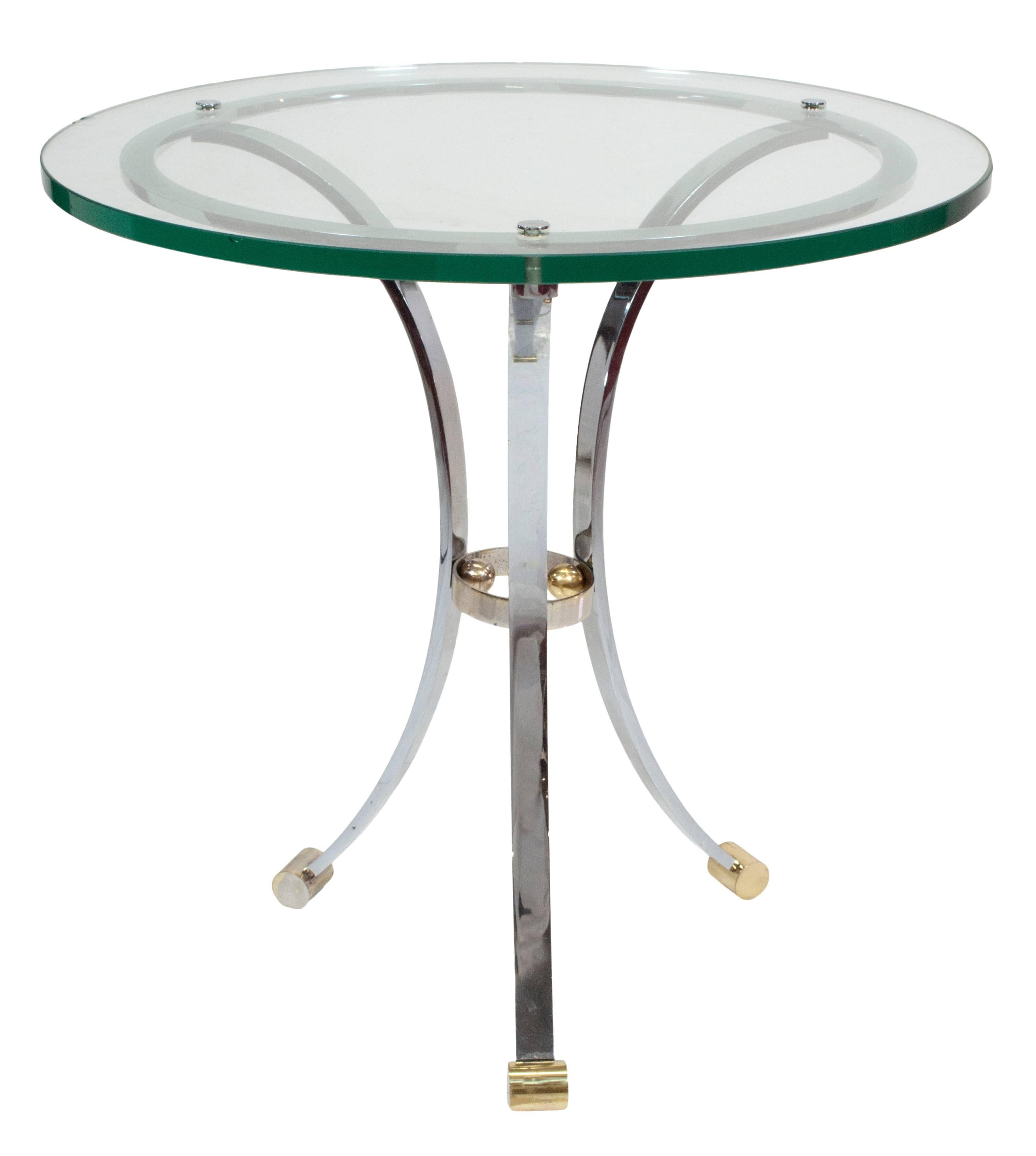 A pair of chrome and glass gueridons with brass detail at the feet and center support.
Minor chips on the edge of one glass top. Photo attached.