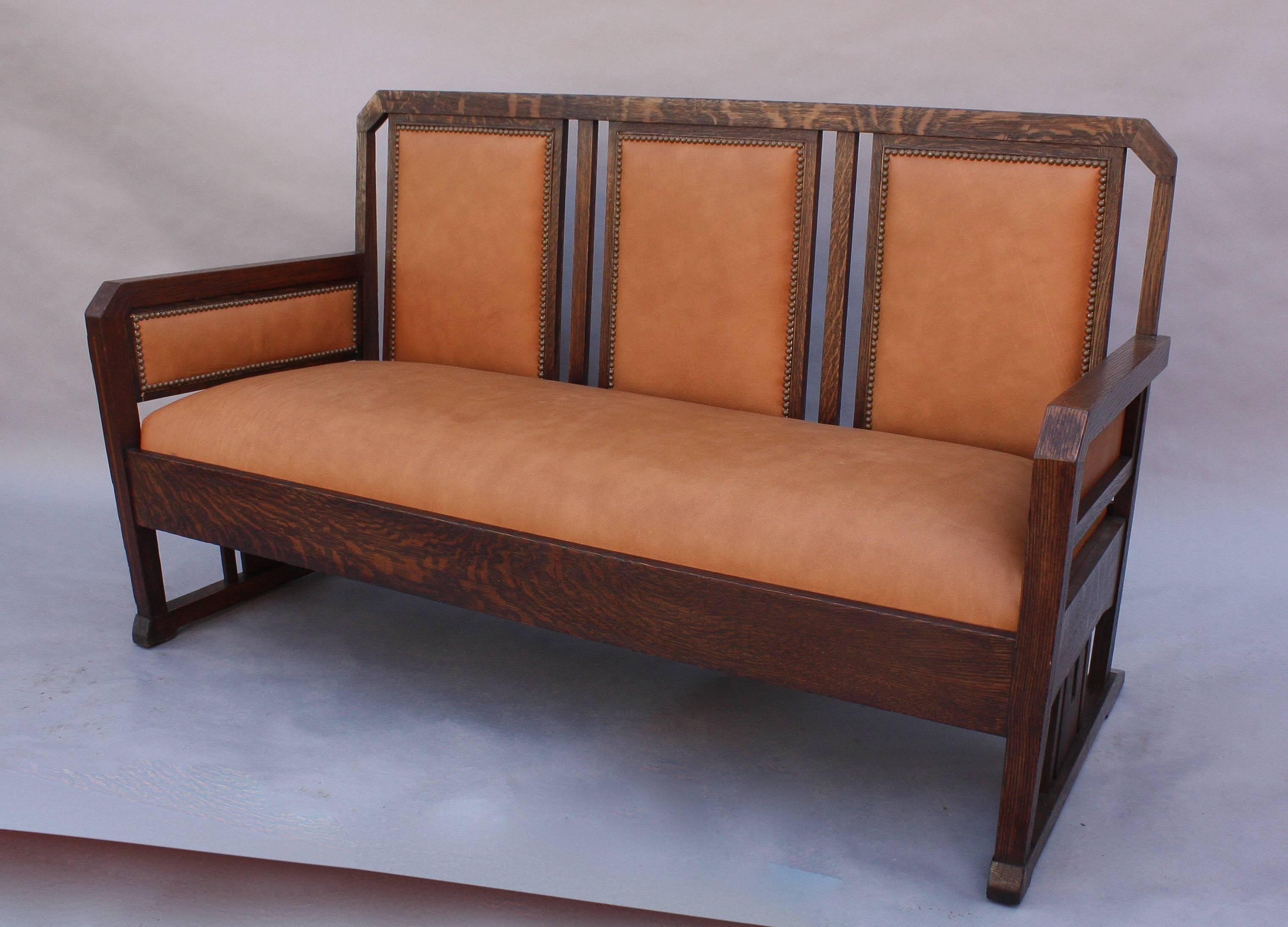 Arts & Crafts period oak settle with new leather upholstery.