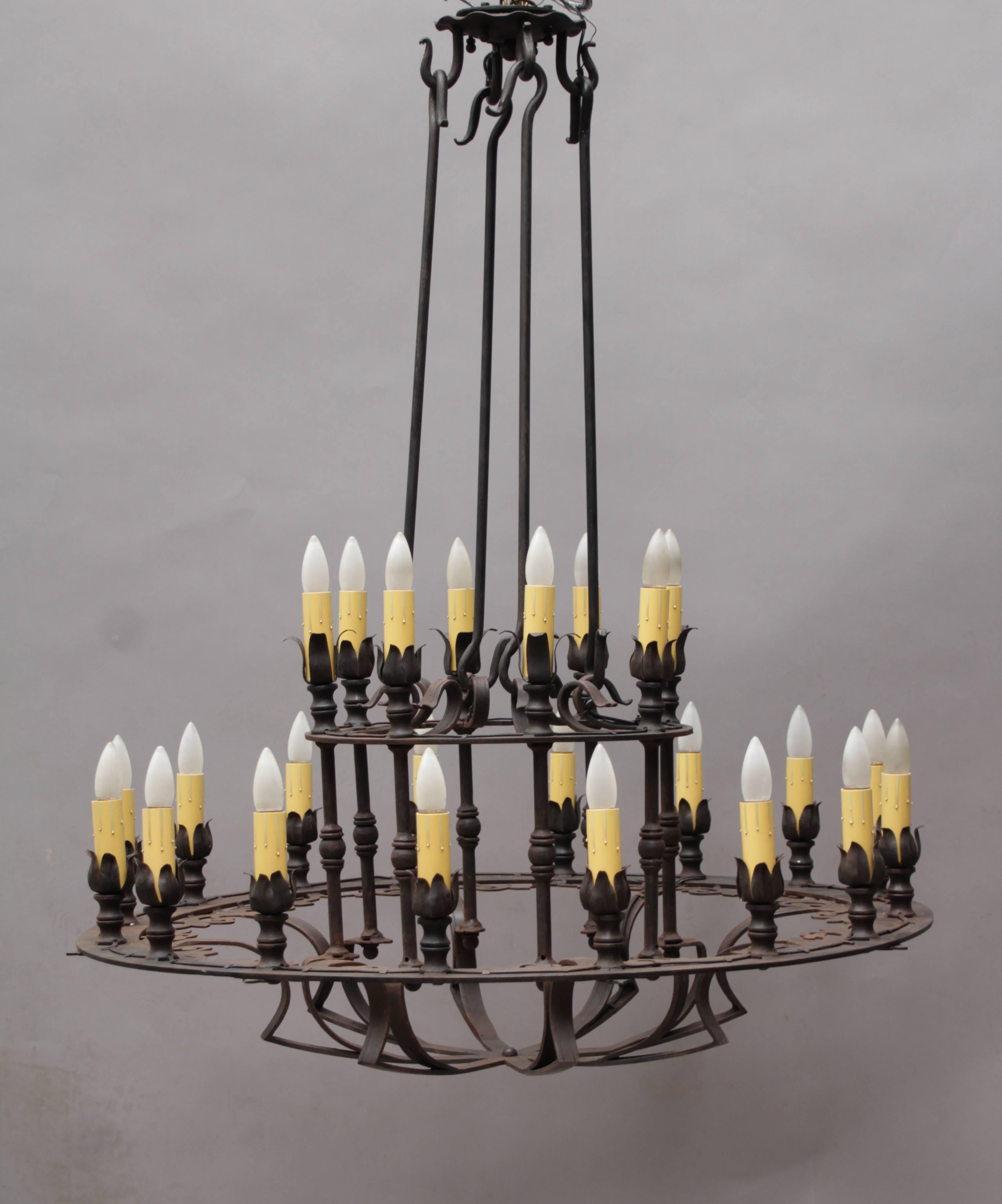 Two-tiered large-scale wrought iron chandelier with incised detailing.