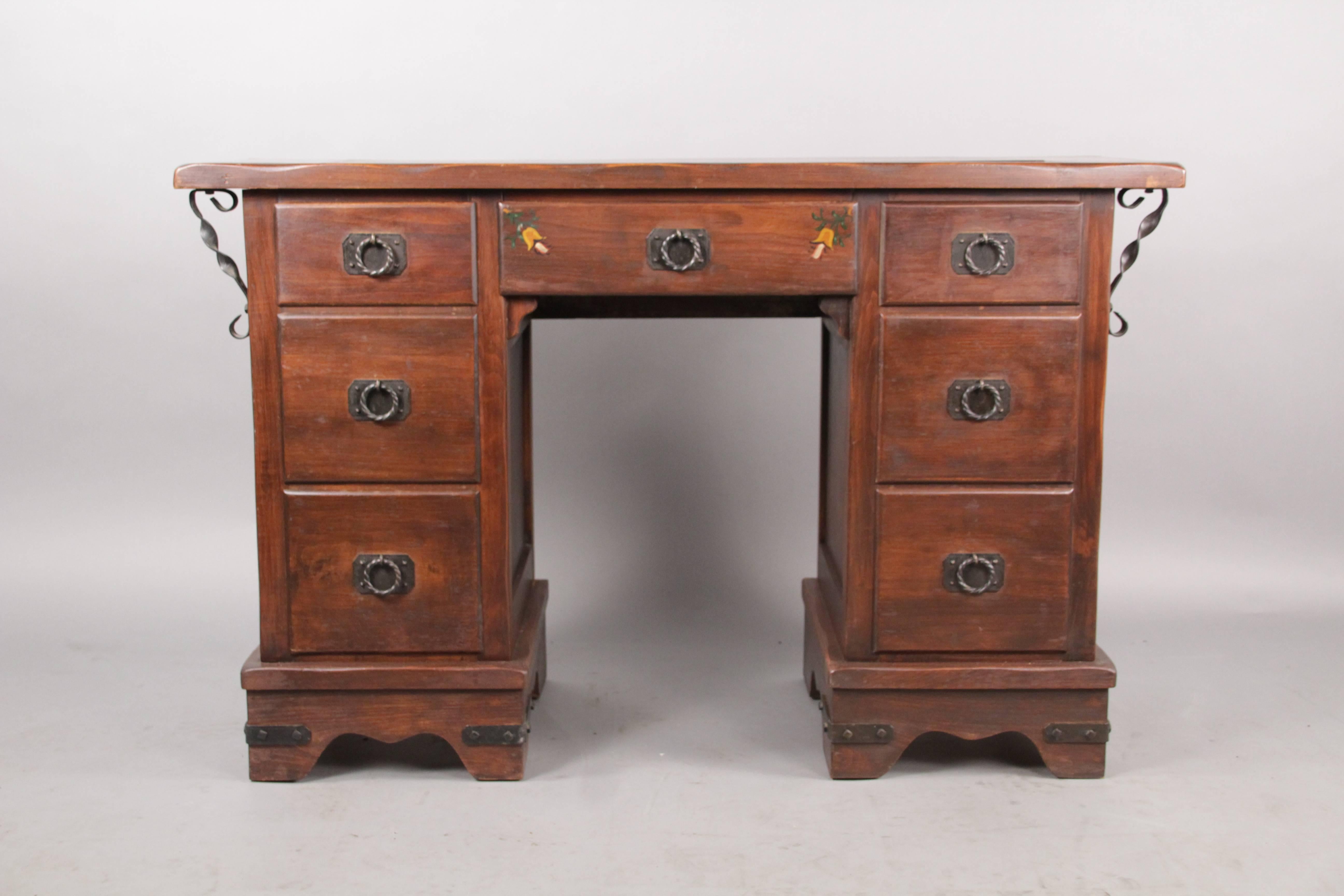 Seven drawer desk with iron detailing and painted detailing, circa 1920s. Retains its original label.