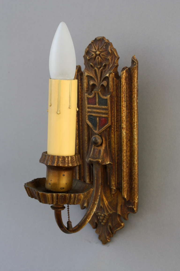 Sconces with original finish, accented with thistle motif and crest or shield in shades of blue and crimson, circa 1920s.