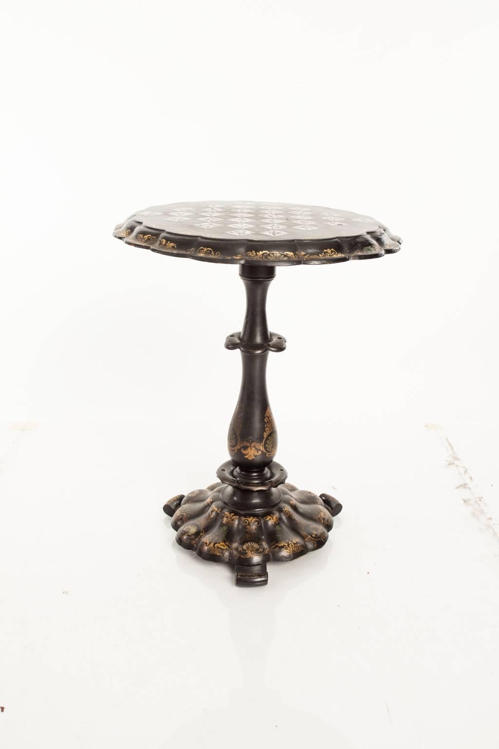 Victorian papier mâché side table in ebonized finish with scalloped apron. Decorated with gold appliqués and mother-of-pearl.