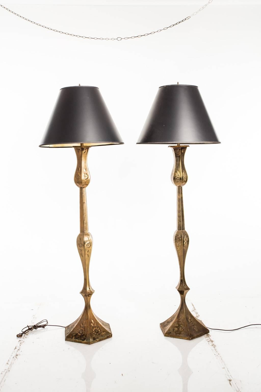 Pair of tall brass floor lamps with repoussé floral motifs throughout.