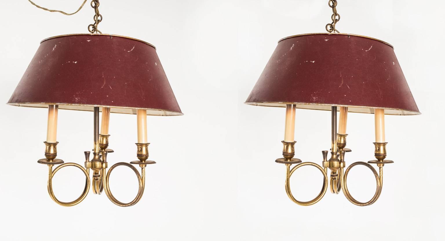 Pair of brass light fixtures with burgundy colored shades.