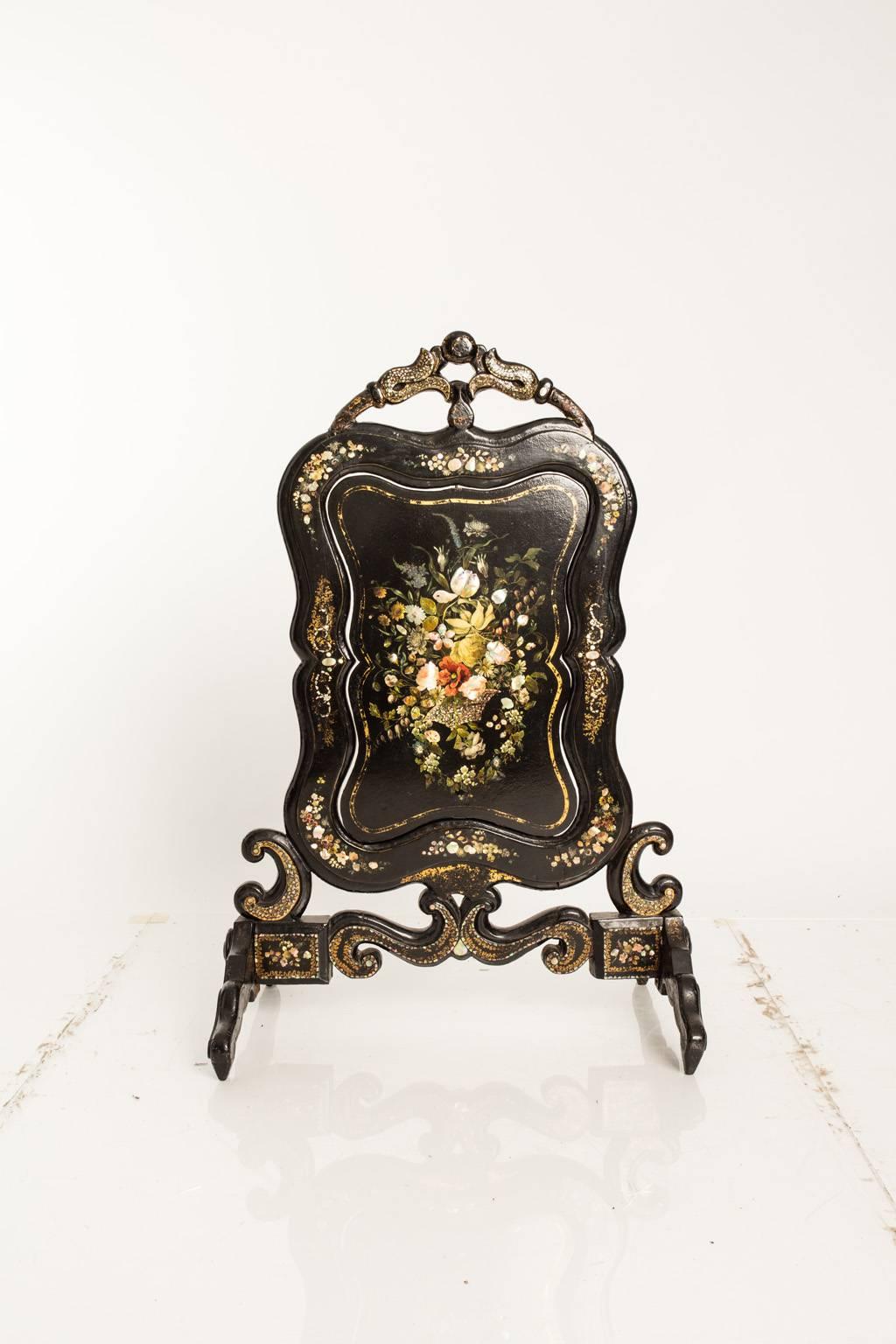 Victorian style fire screen with a floral motif decoration on its front.