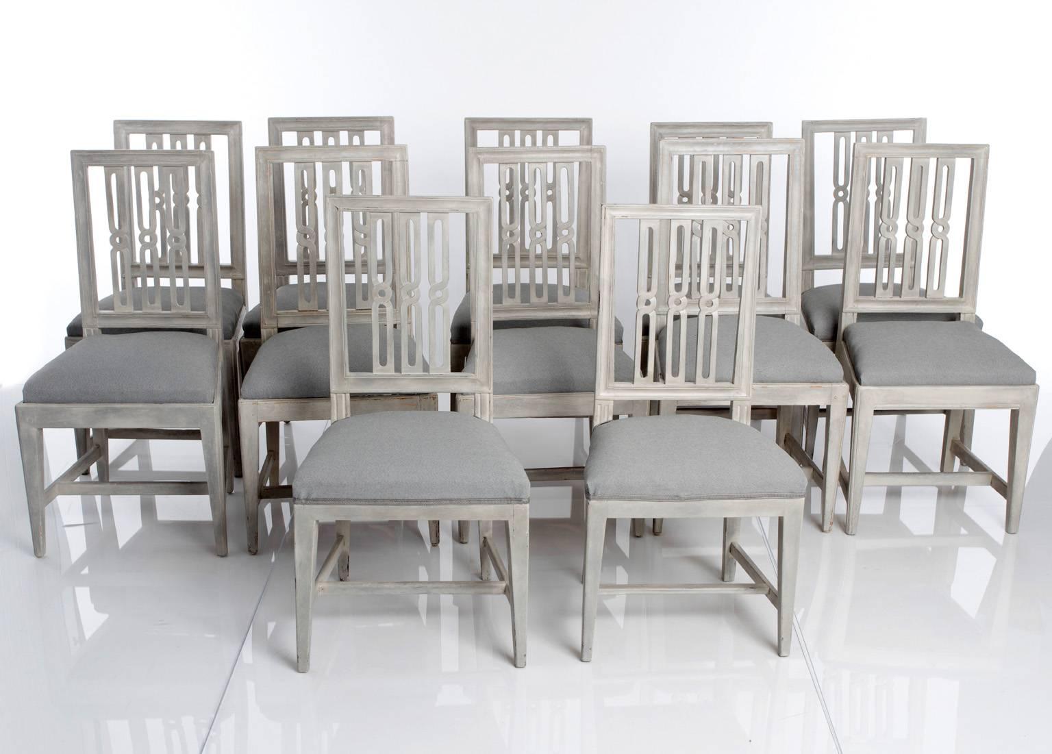 Swedish, late 1700s-early 1800s. Signed Erik Holm, Stockholm master chair-maker 1774-1814. A set of 12 grey-painted Gustavian dining chairs. Open-work backs with simple geometrical shapes. Straight tapered legs with cross stretchers.
   