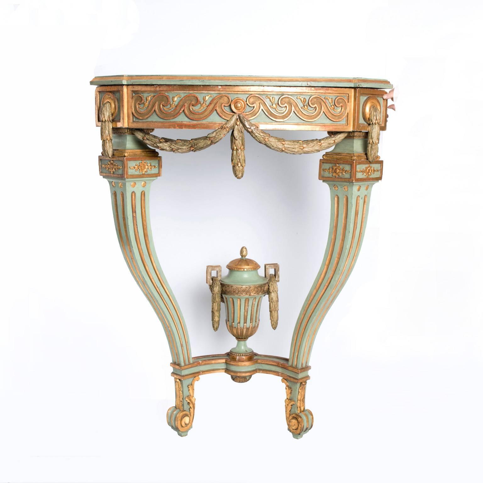 18th century grand green painted and gilded Gustavian corner console table. Apron with gilt wave-like carvings and a gilt carved leaf-garland. Two square fluted cabriole legs with scrolled feet. Stretcher with a large urn finial with gilt carved
