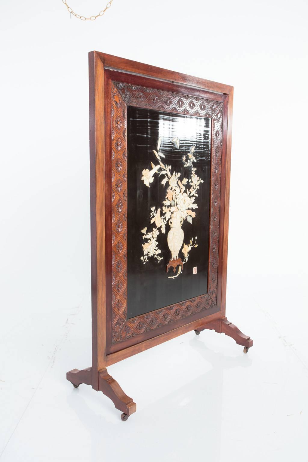 Early 19th century Asian floor screen with intricate mother-of-pearl and bone details. At the center of the panel sits a spray of expertly carved flowers with lively birds and butterflies peeking among the petals. A signature is similarly carved.