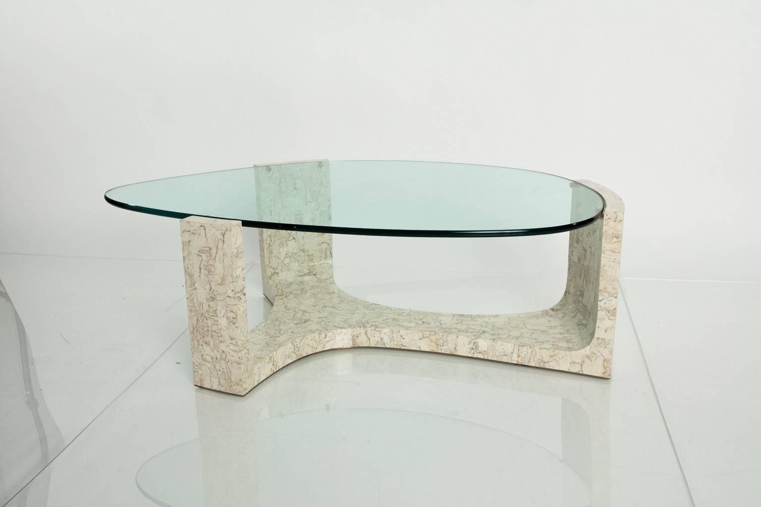 Kidney shaped, three prong coffee table with a glass top.