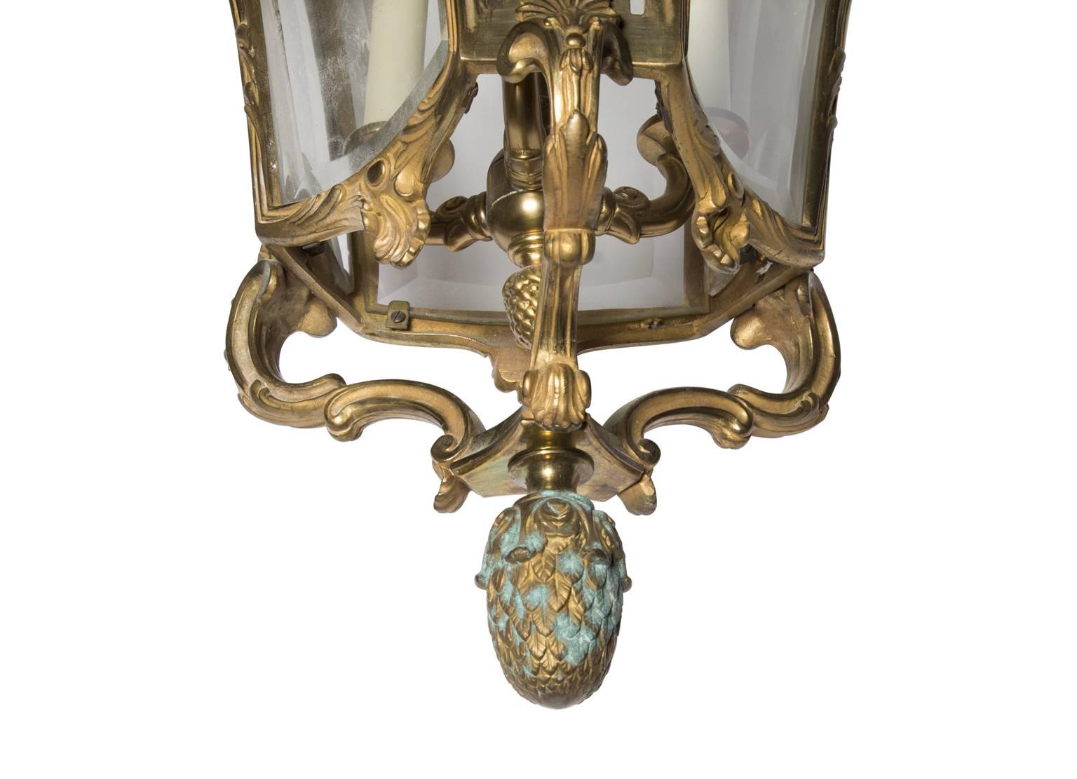 Tulip shaped lantern composed of bronze and glass. The bottom of the lantern is capped by a leafy finial.
 