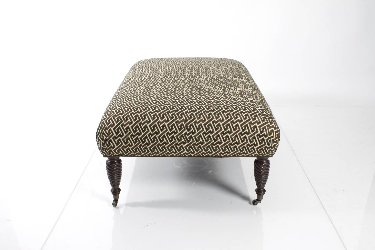 Ottoman upholstered in brown and white, geometric patterned fabric.
  