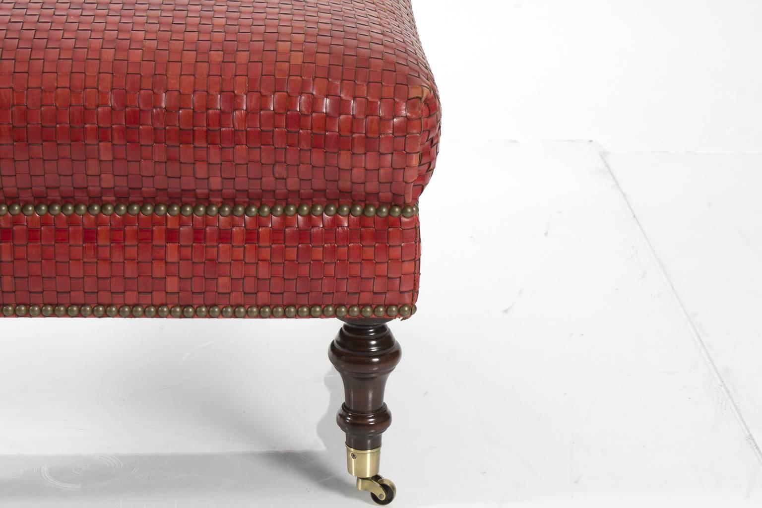 Woven red leather ottoman with nailhead details, on casters. Maker-Edward Ferrell.
 