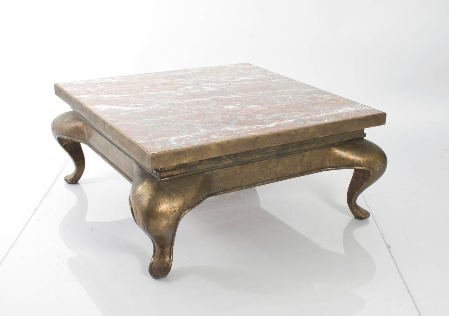 Low coffee table with a marble top on top of a faux gold painted base and cabriole legs.
  