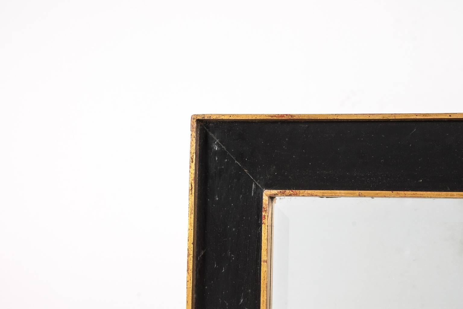 20th century beveled glass mirror in rectangular black and gilt frame.