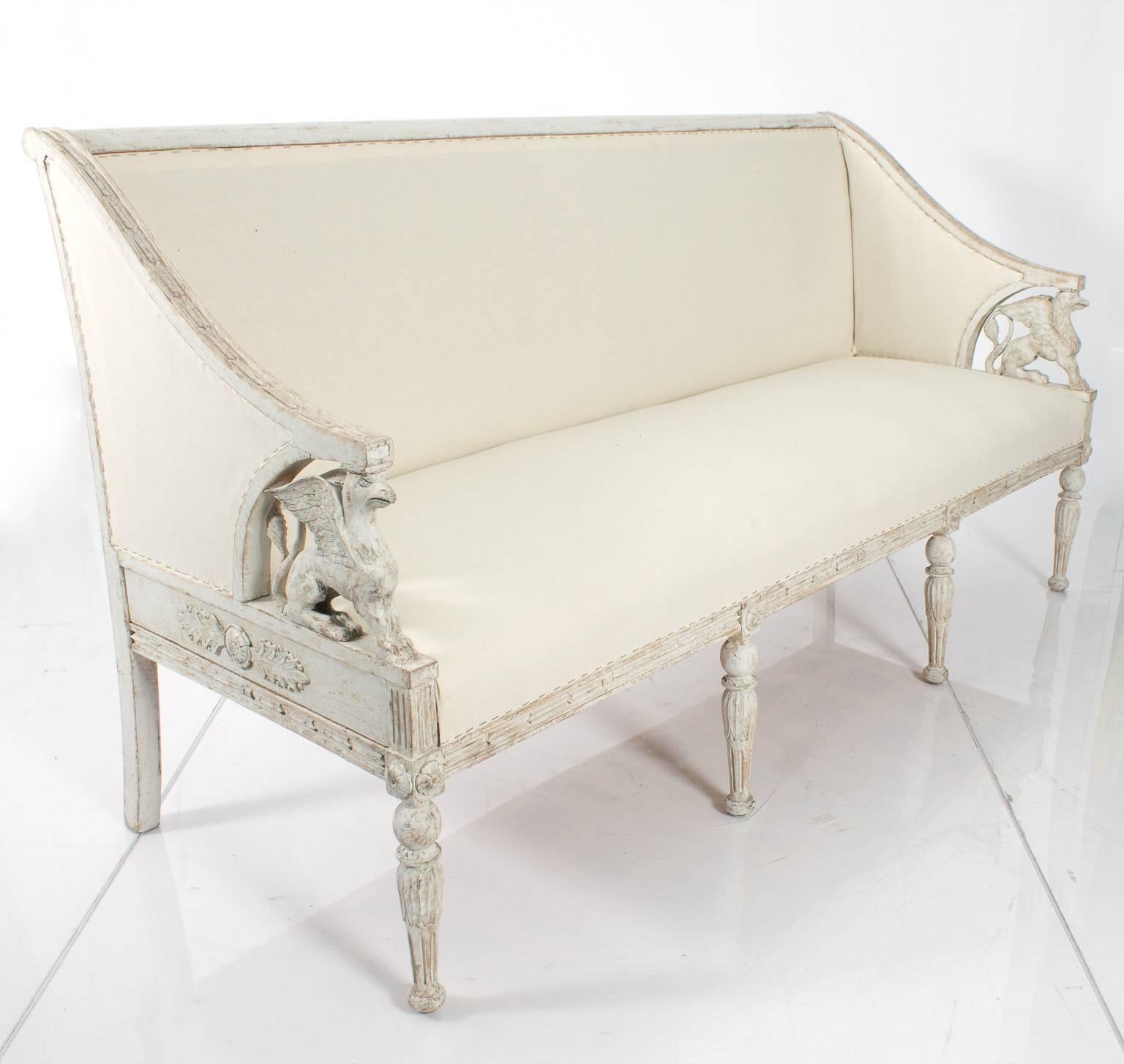 19th century Swedish white-painted Gustavian style sofa straight back armrests carved with griffins with rounded legs.