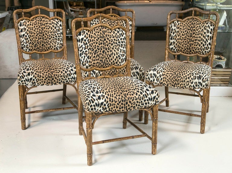 Set of four faux bamboo chairs in leopard print fabric with distressed finish.