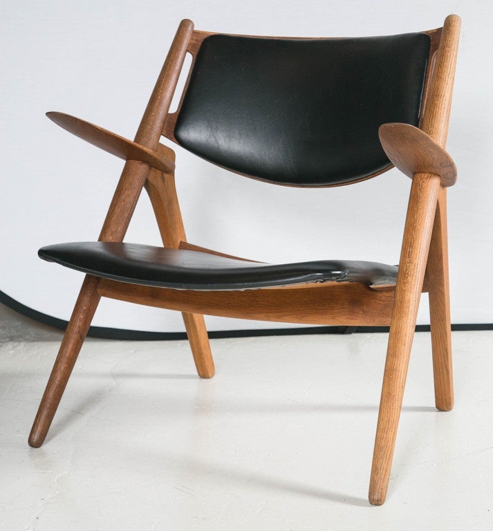 The iconic sawback chairs by Hans Wegner, is a staple piece in the Mid-Century era. An early production, stamped original black Naugahyde seat and back, it bears the marking Made in Denmark Carl Hansen & Son Odense Denmark, Designer Hans J. Wegner.