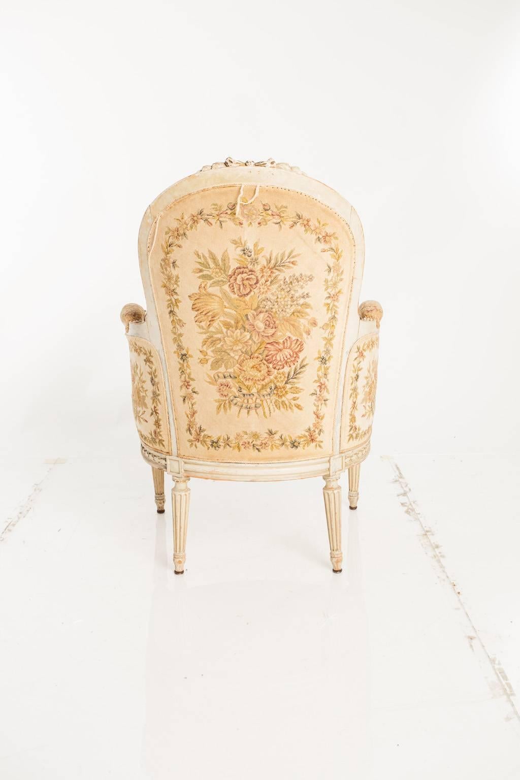 A pair of bergère chairs. Upholstery is decorated with a needlepoint floral motif.