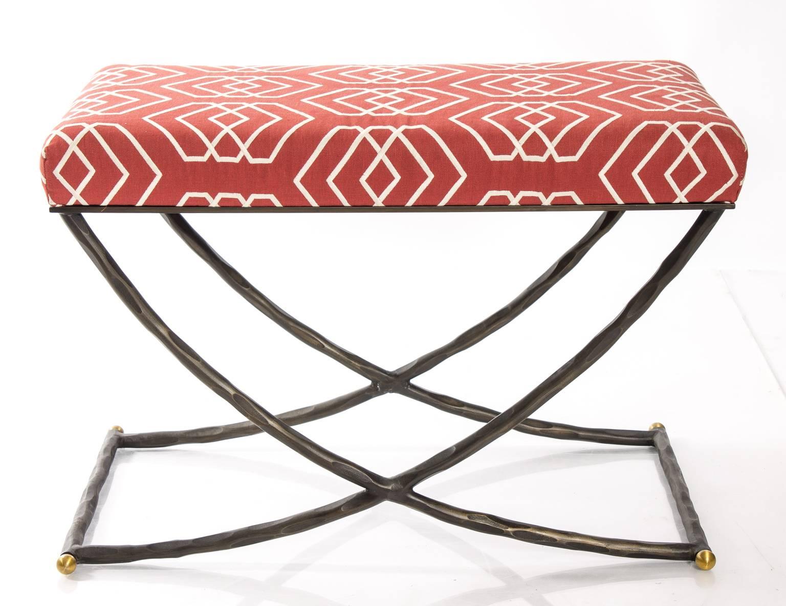 Bronzed iron X-bench with brass details. The top is upholstered in red fabric by Brunschwig & Fils.