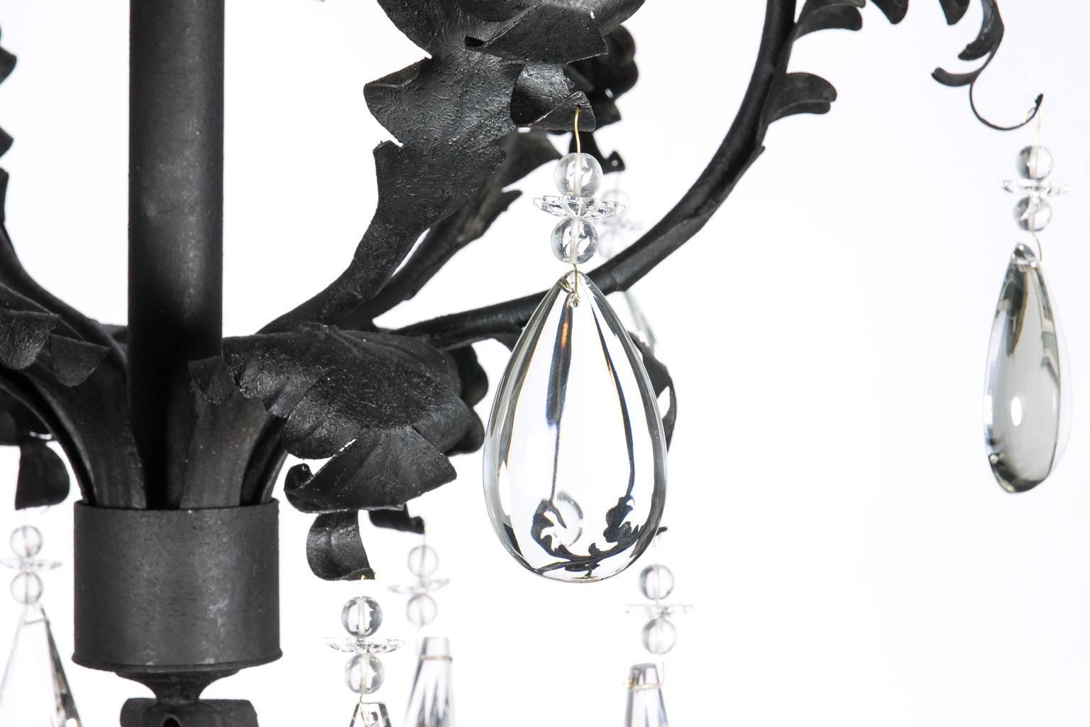 Six black wrought iron foliate arms with brass details and large-scale crystal pendants, circa 1990s. Maker: Harte lighting, USA.
 