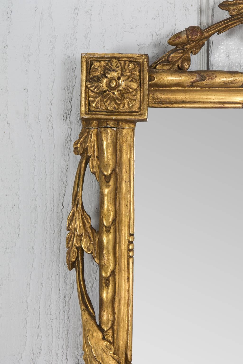 Gilded neoclassical mirror with crossed wheat pediment. On each corner is featured a carved rosette.