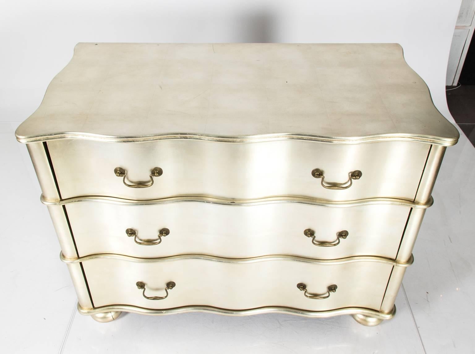 Contemporary silver leaf serpentine three-drawer chest with metal pulls.
 