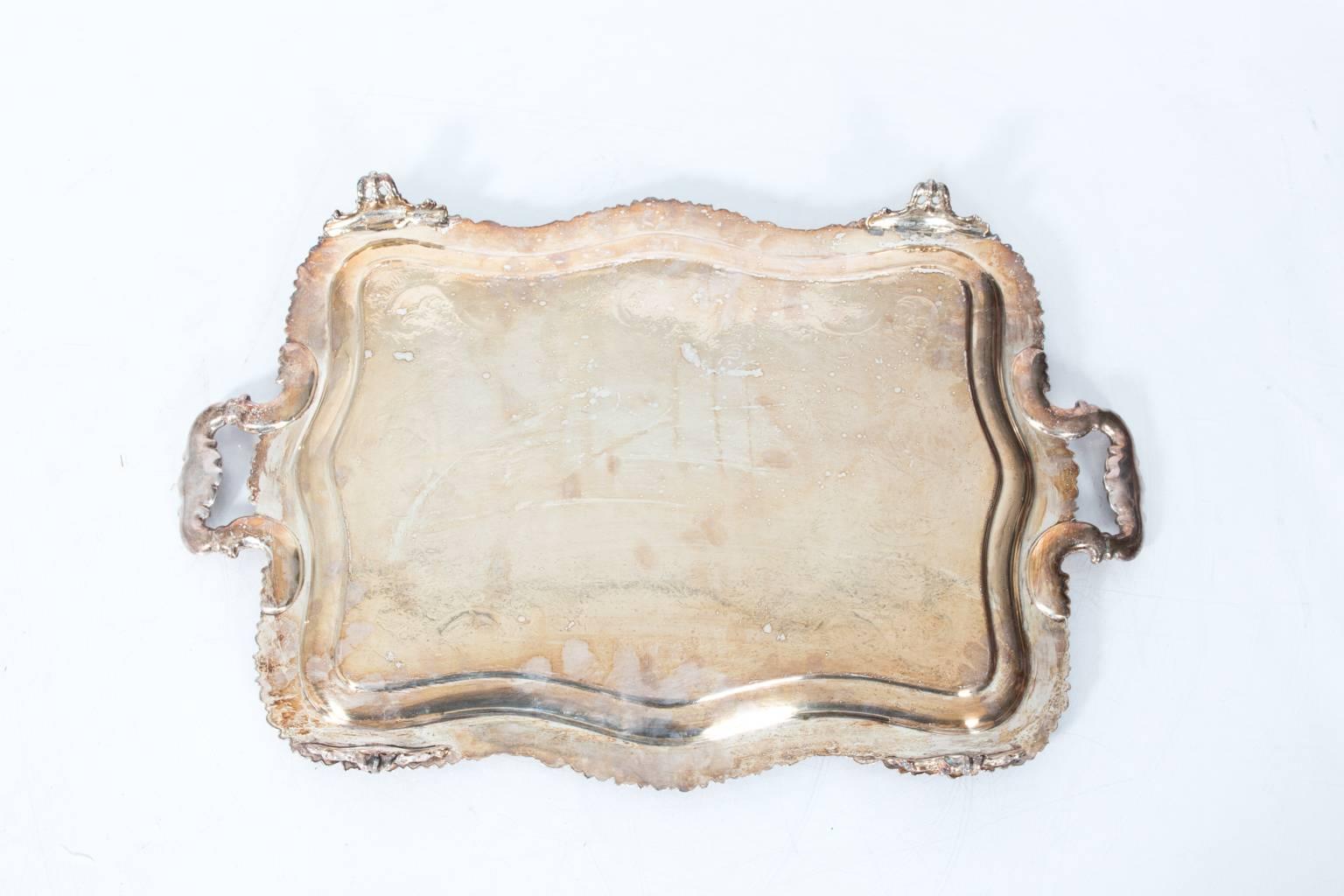 Silver plated serving tray with floral etching and handles.
  