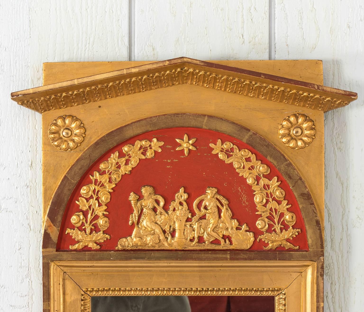 Early 19th century Gustavian Style red painted mirror with gold gilt. The frame features a carved raking cornice, rosettes and a beaded trim.
 