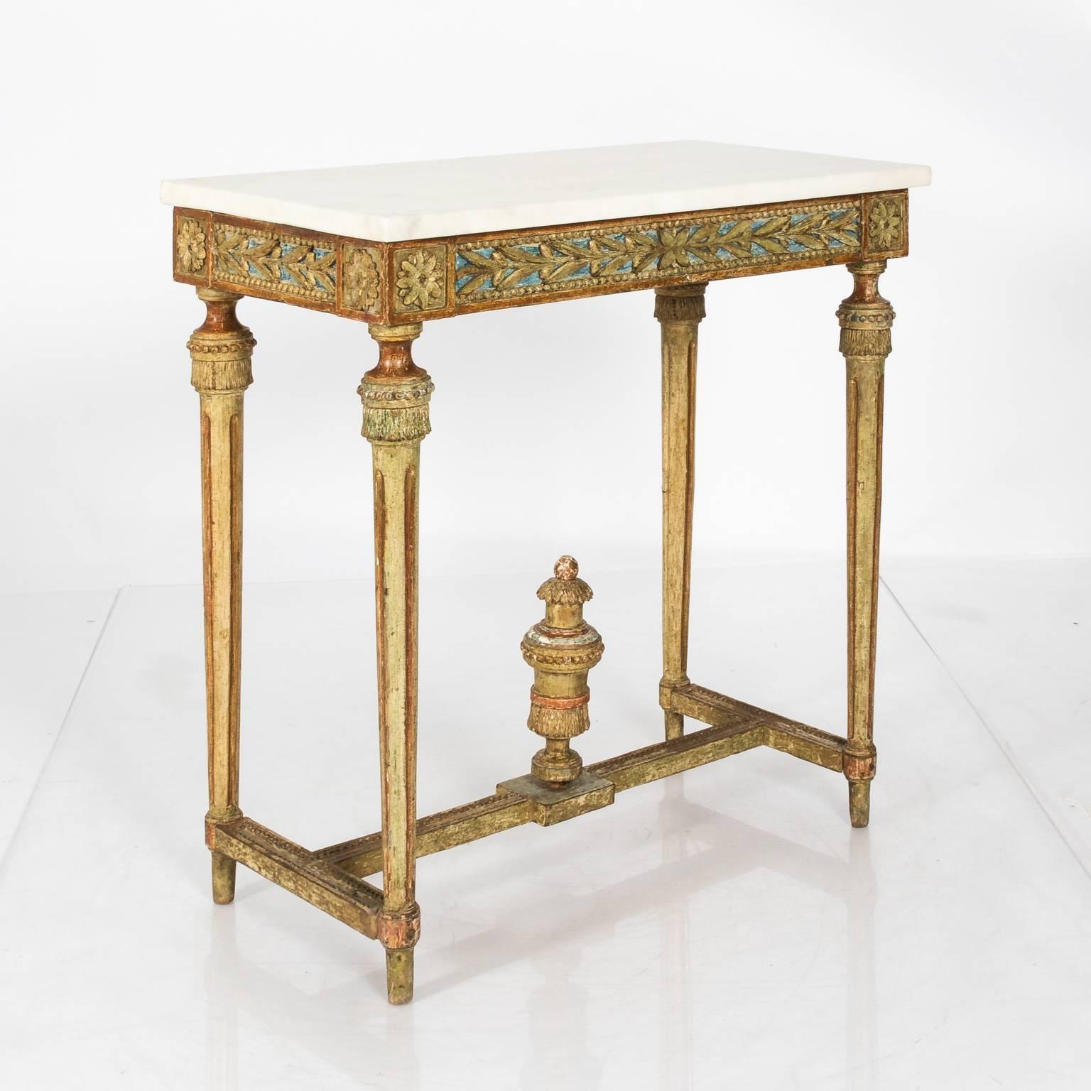 A giltwood Gustavian console table with a white marble top, carved frieze with foliage and rosettes.
    