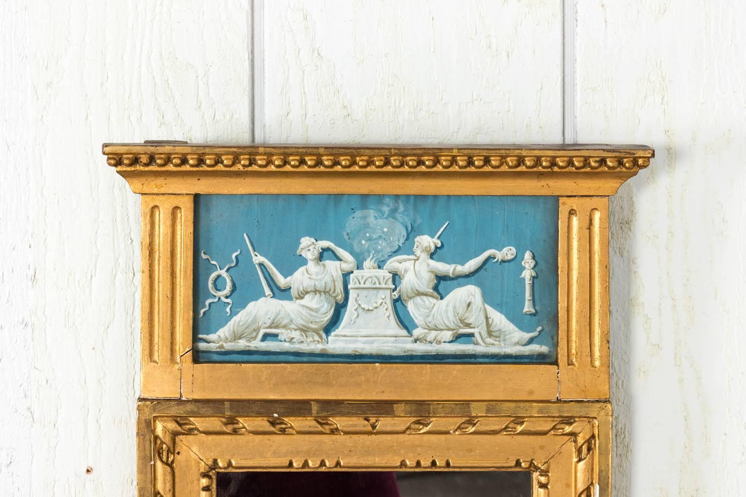A giltwood Gustavian mirror with white inlayed antiquity motif on blue-painted background.
  