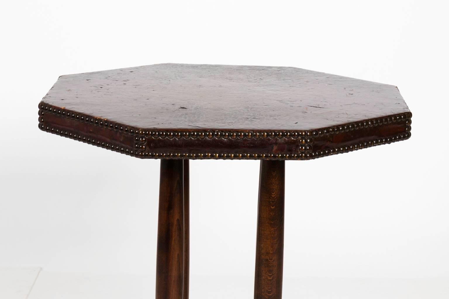 French Art Deco table that features a leather top with brass head trim, circa early 20th century. There is minor wear on the leather top.