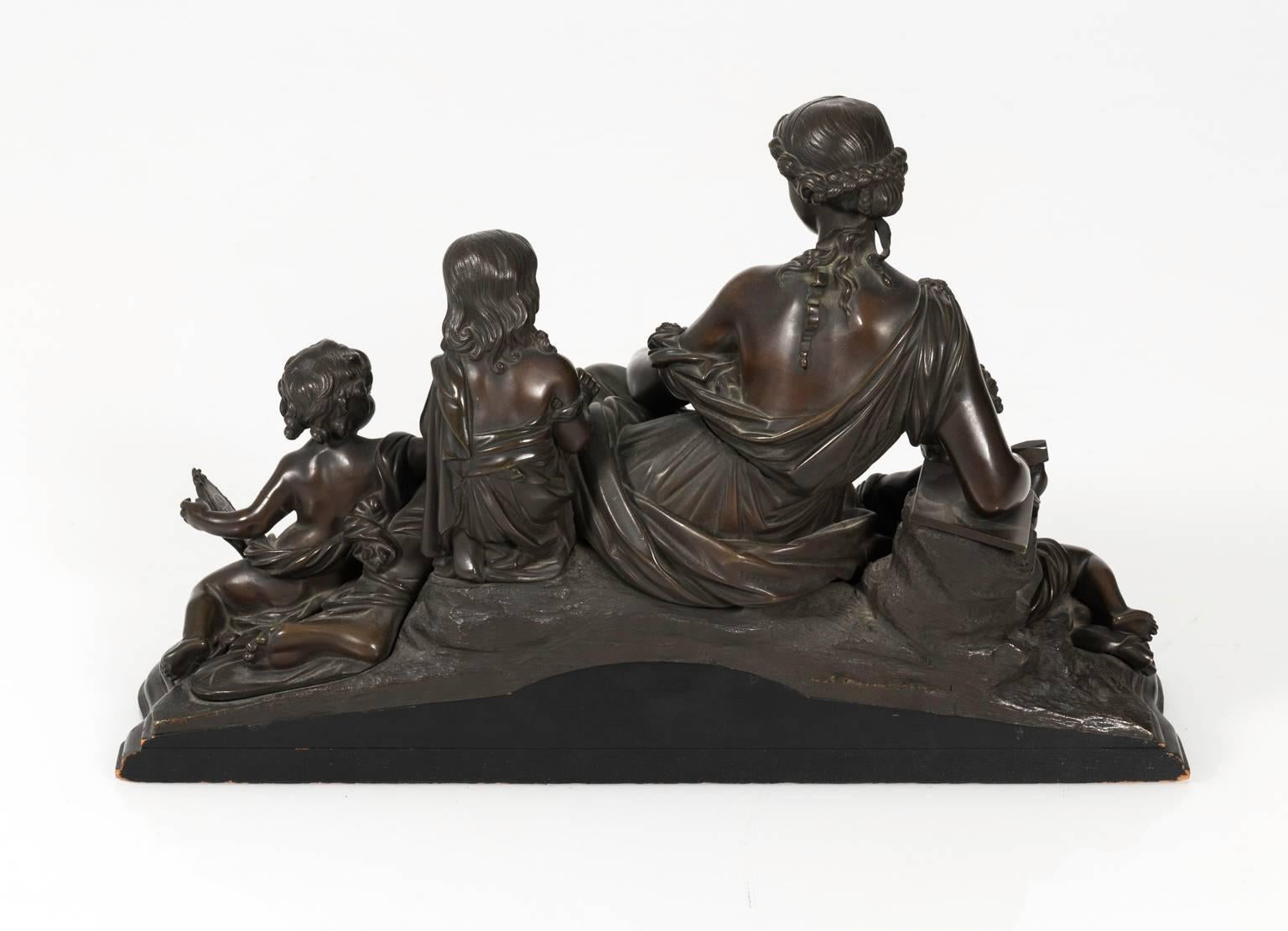 Early 20th century bronze statue depicting allegory on art. Reclining goddess in company of three putti representing painting, sculpture and architecture. Cast bronze on a wooden base.