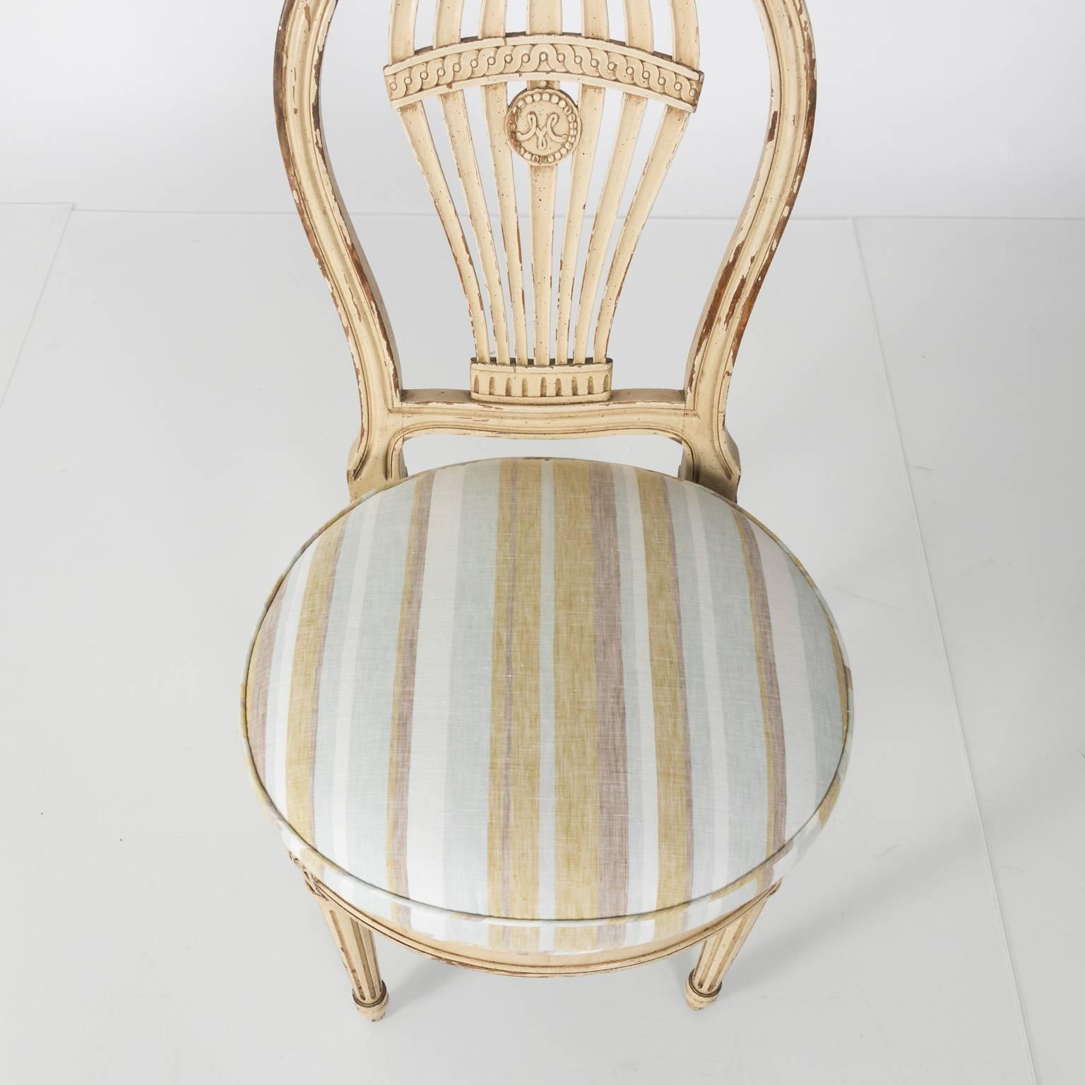 Set of four French pierced balloon back side chairs with newly reupholstered round seats in a soft striped linen fabric, circa 1920.